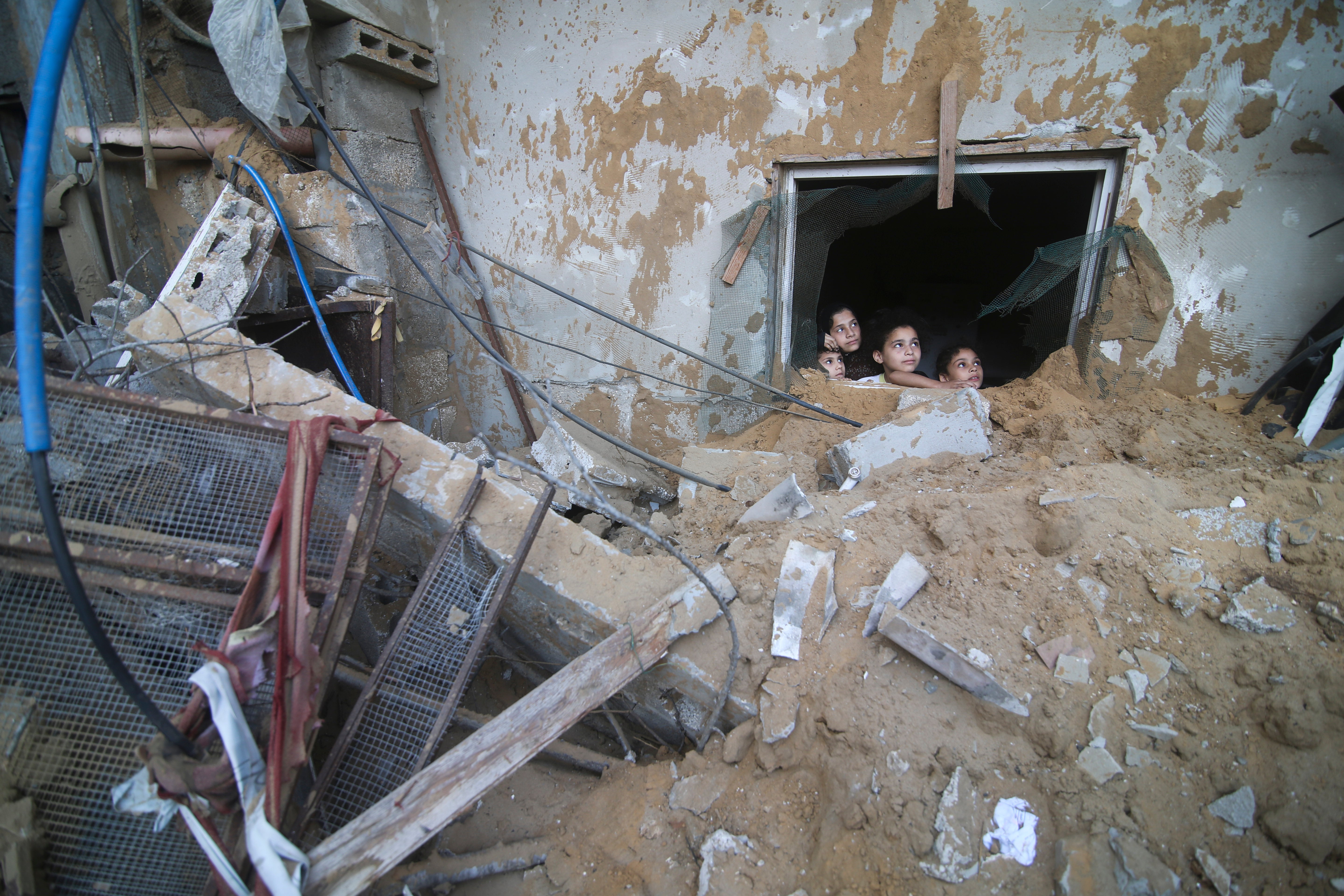 Palestinian children look at the building of the Zanon family, destroyed in Israeli airstrikes in Rafah