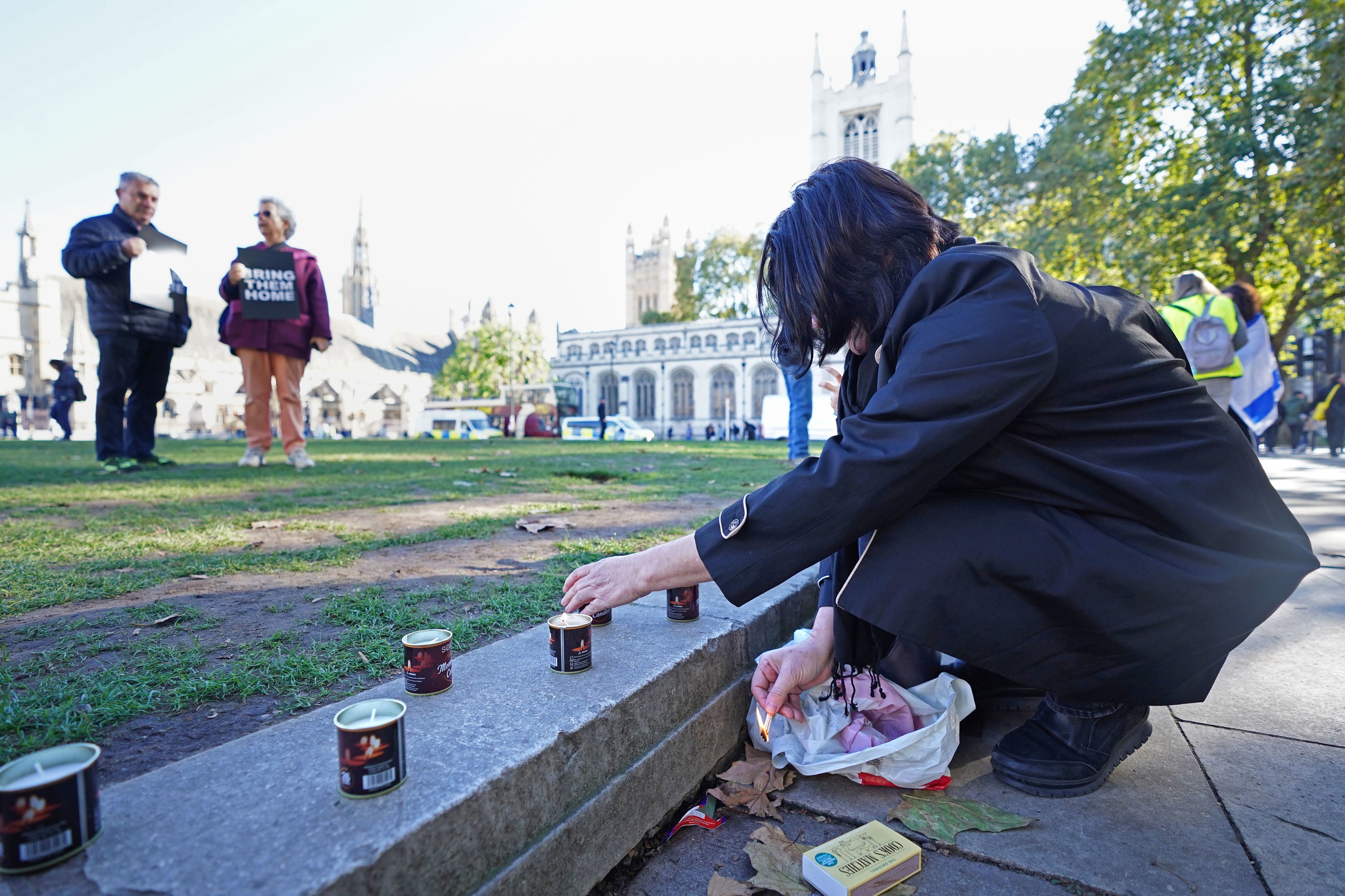 A woman lights a candle a vigil at Parliament Square