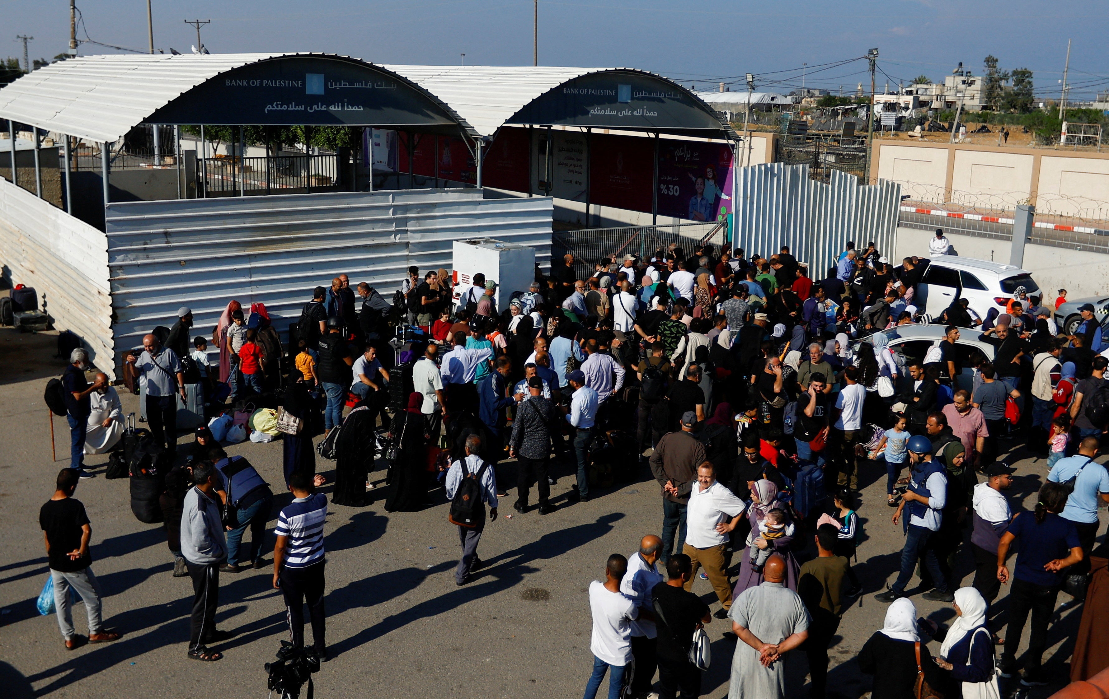 Palestinians with dual citizenship gather at the Rafah border crossing with Egypt