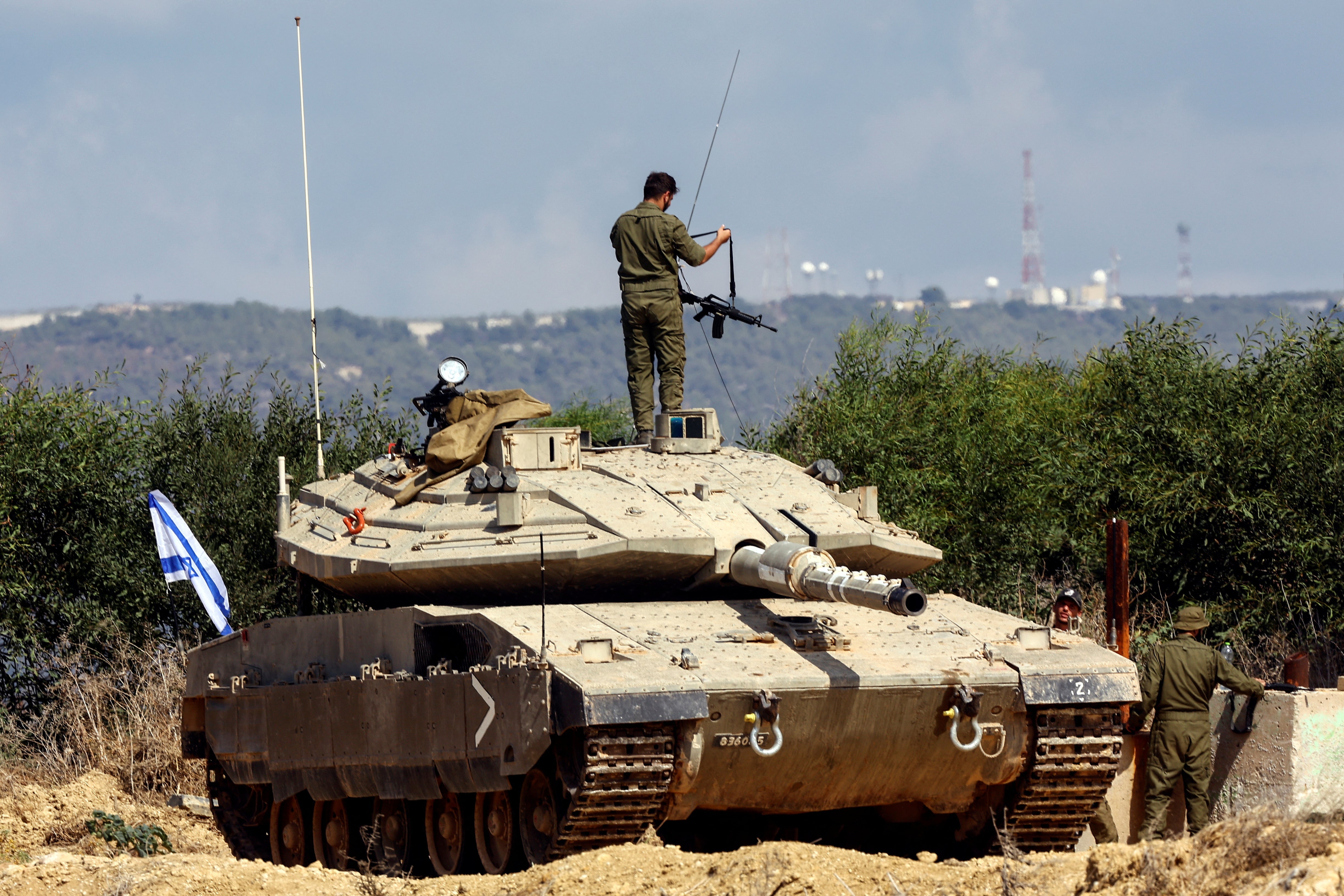An Israeli soldier adjusts his rifle as he stands on a tank near Israel's border with Lebanon