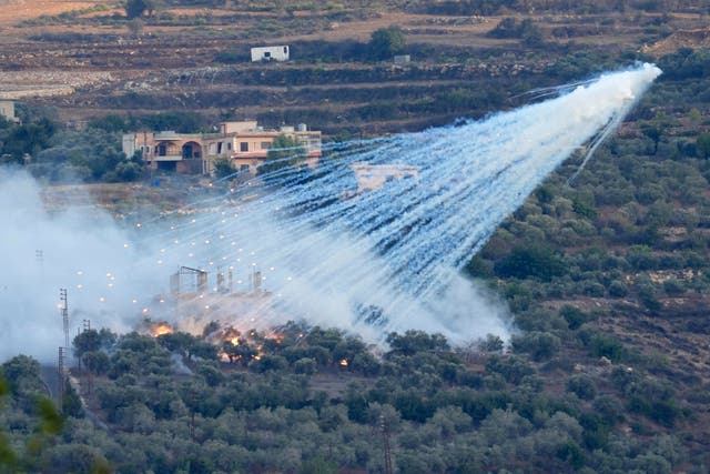 <p>A shell from Israeli artillery explodes over a house in al-Bustan, a Lebanese border village with Israel</p>