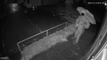 CCTV shows a figure in a mask and carrying an umbrella before throwing the red paint