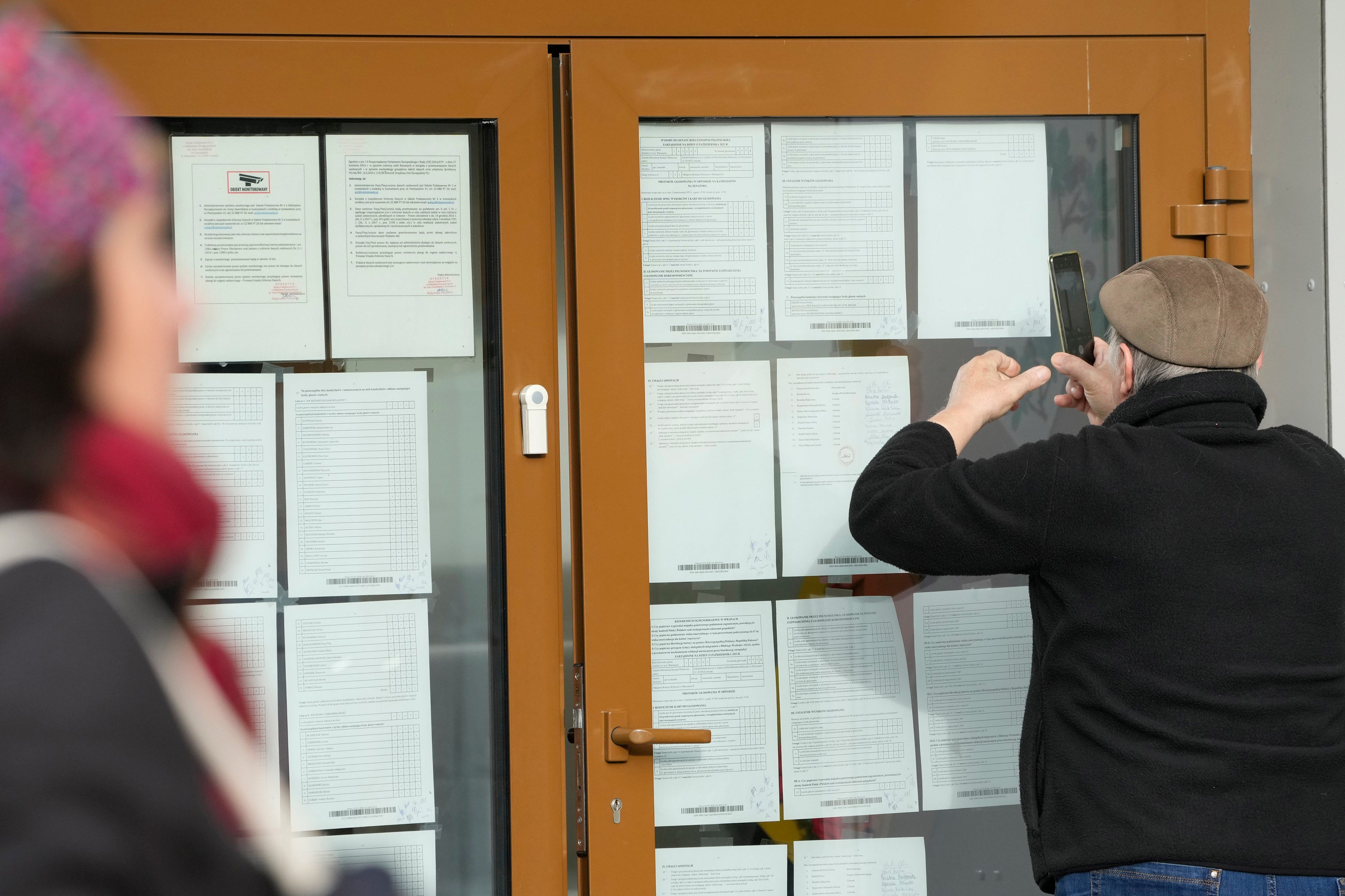 A man checks the results of Sunday’s parliamentary elections in Poland