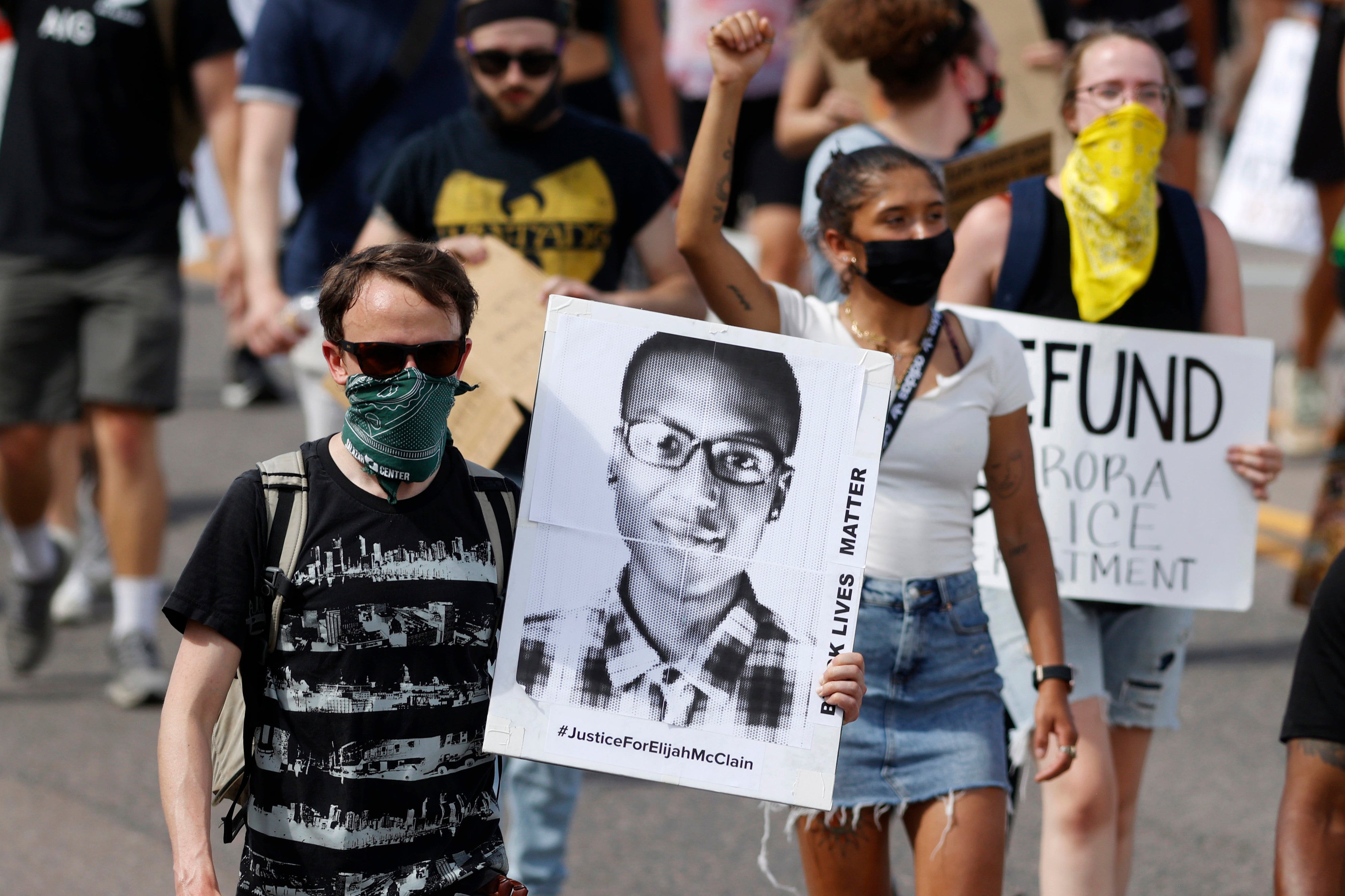 A demonstrator carries an image of Elijah McClain during a rally and march in Aurora in 2020