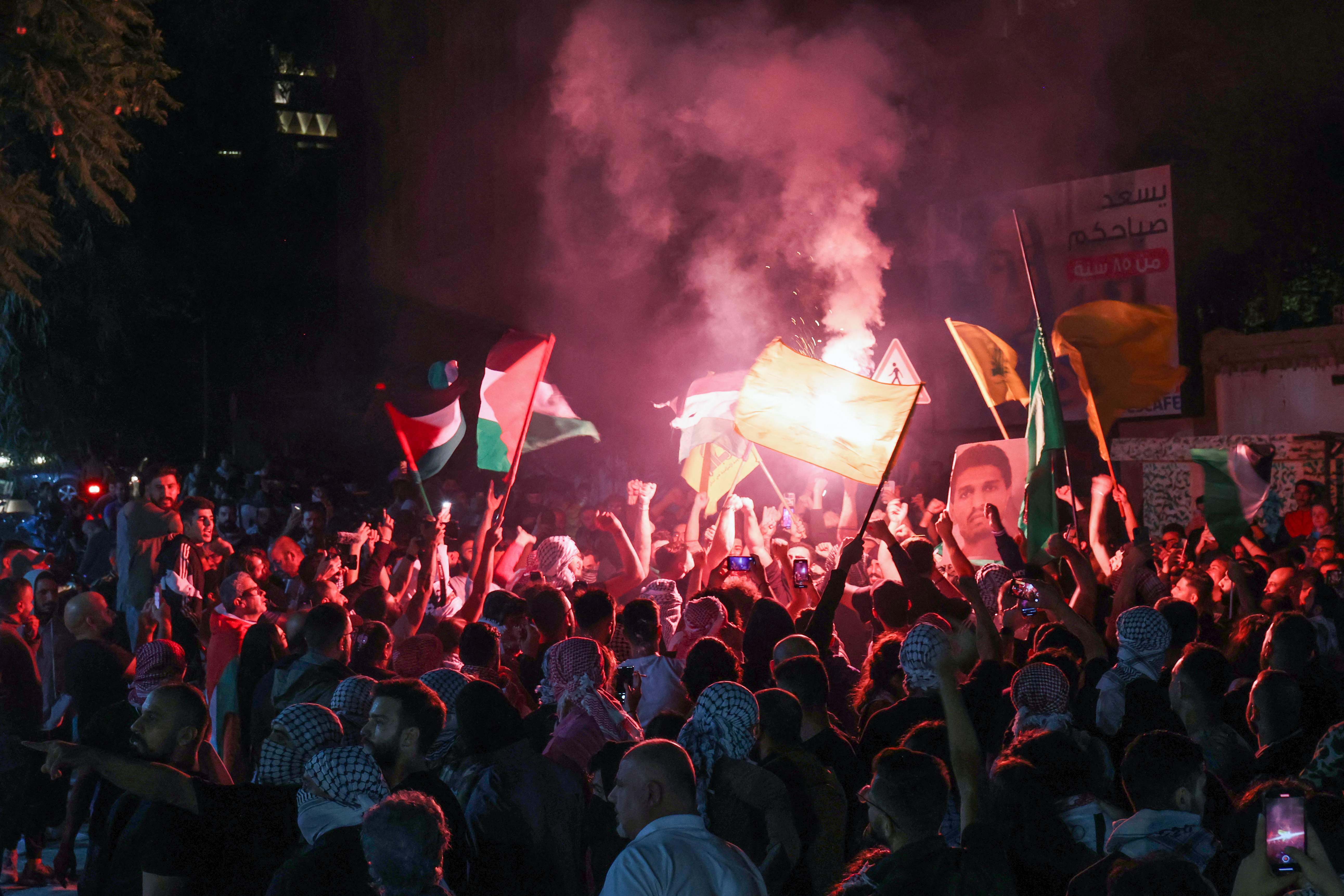Protesters lift Palestinian flags and a portrait of Mohammed Deif chief of Al-Qassam Brigades, Hamas' military wing, during rally at the entrance of the French embassy complex in Beirut