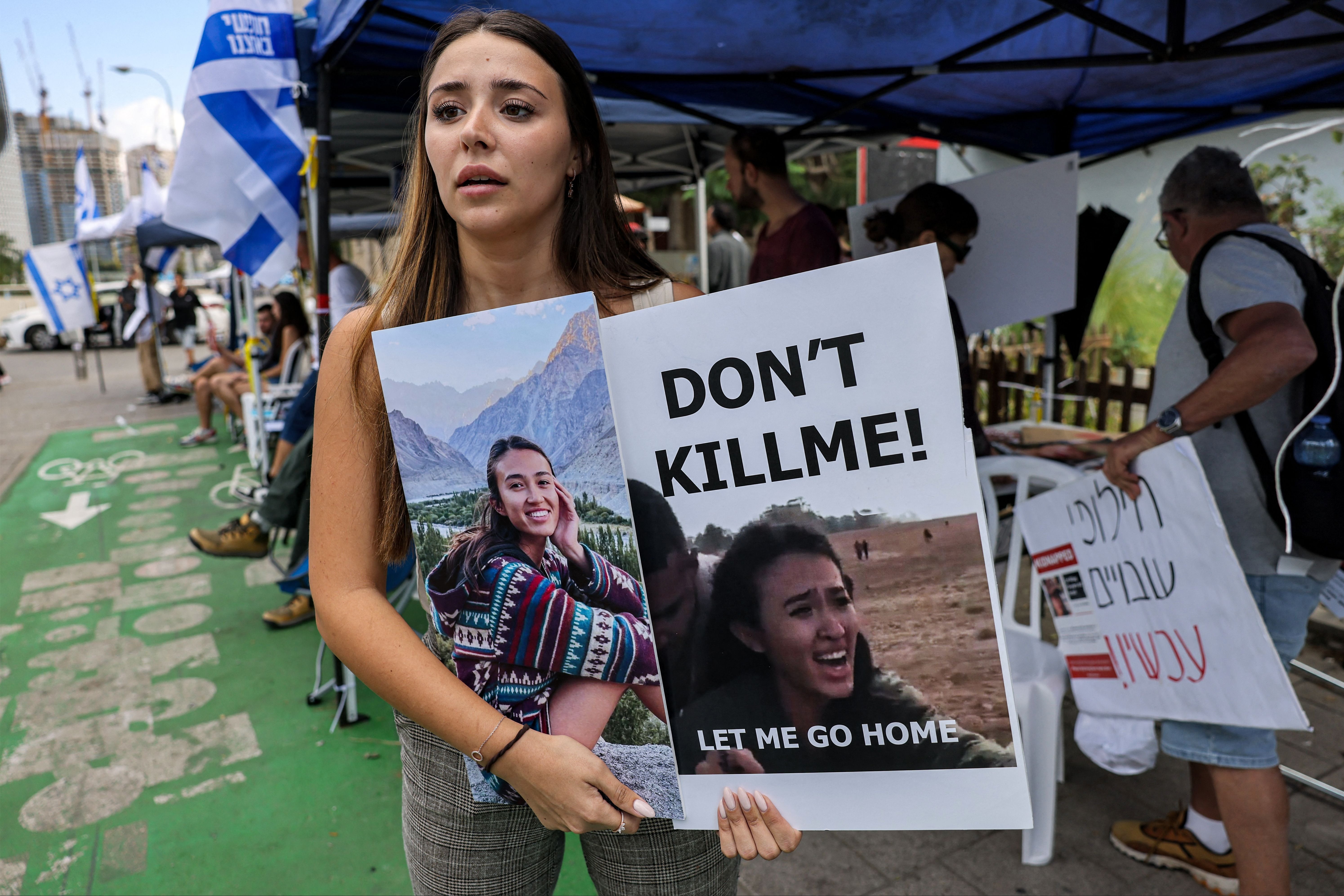 A friend of Israeli student Noa Argamani, one of the Israeli hostages held by Hamas, stands with a sign showing her face
