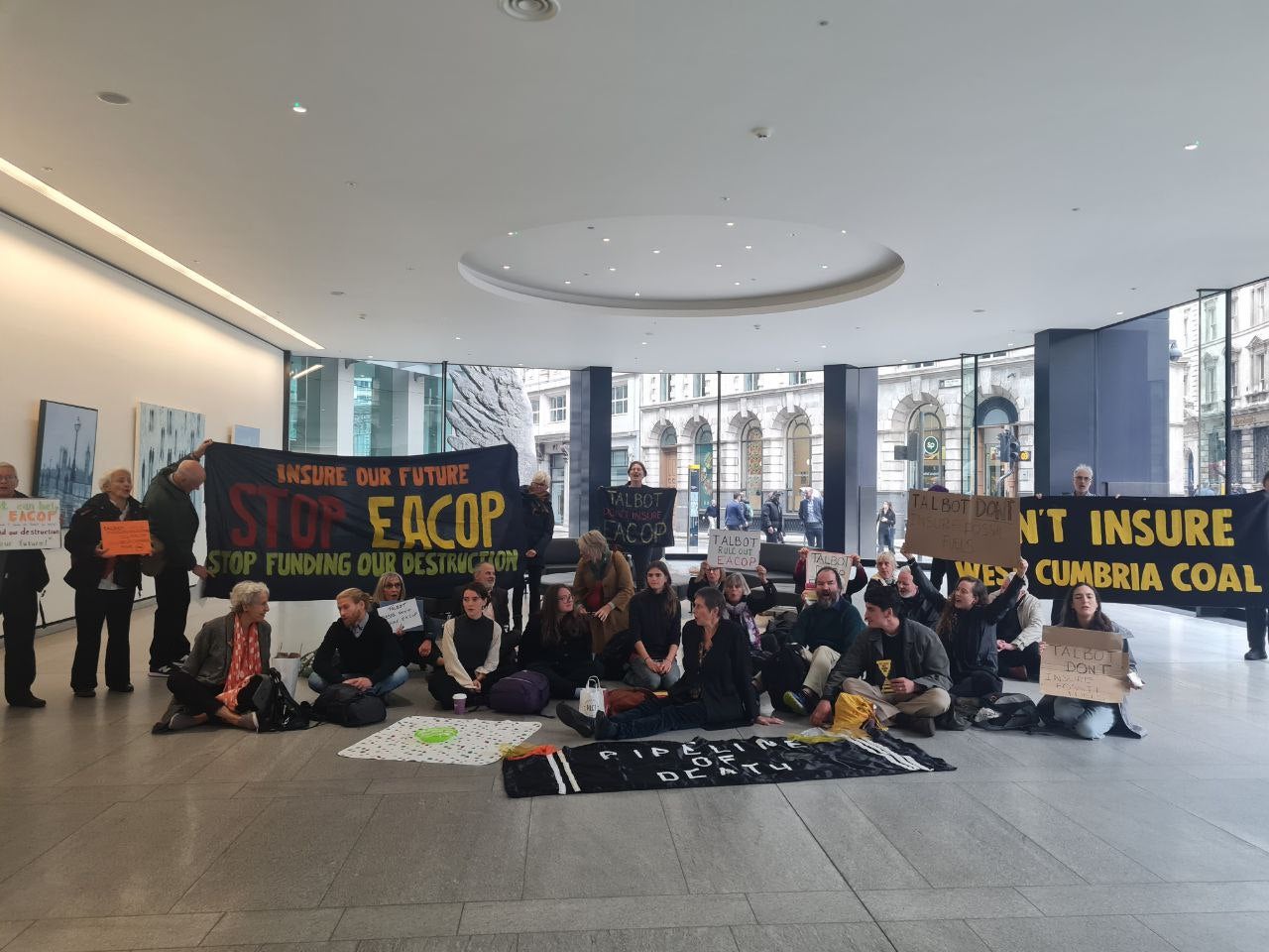 Fossil Free London protestors inside the office Talbot Insurance holding banners saying ‘Don’t Insure EACOP’ and ‘Don’t Insure West Cumbria Mine’
