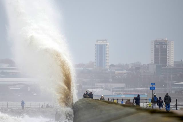 <p>People view the waves created by high winds and spring tides hitting the sea wall at New Brighton promenade</p>