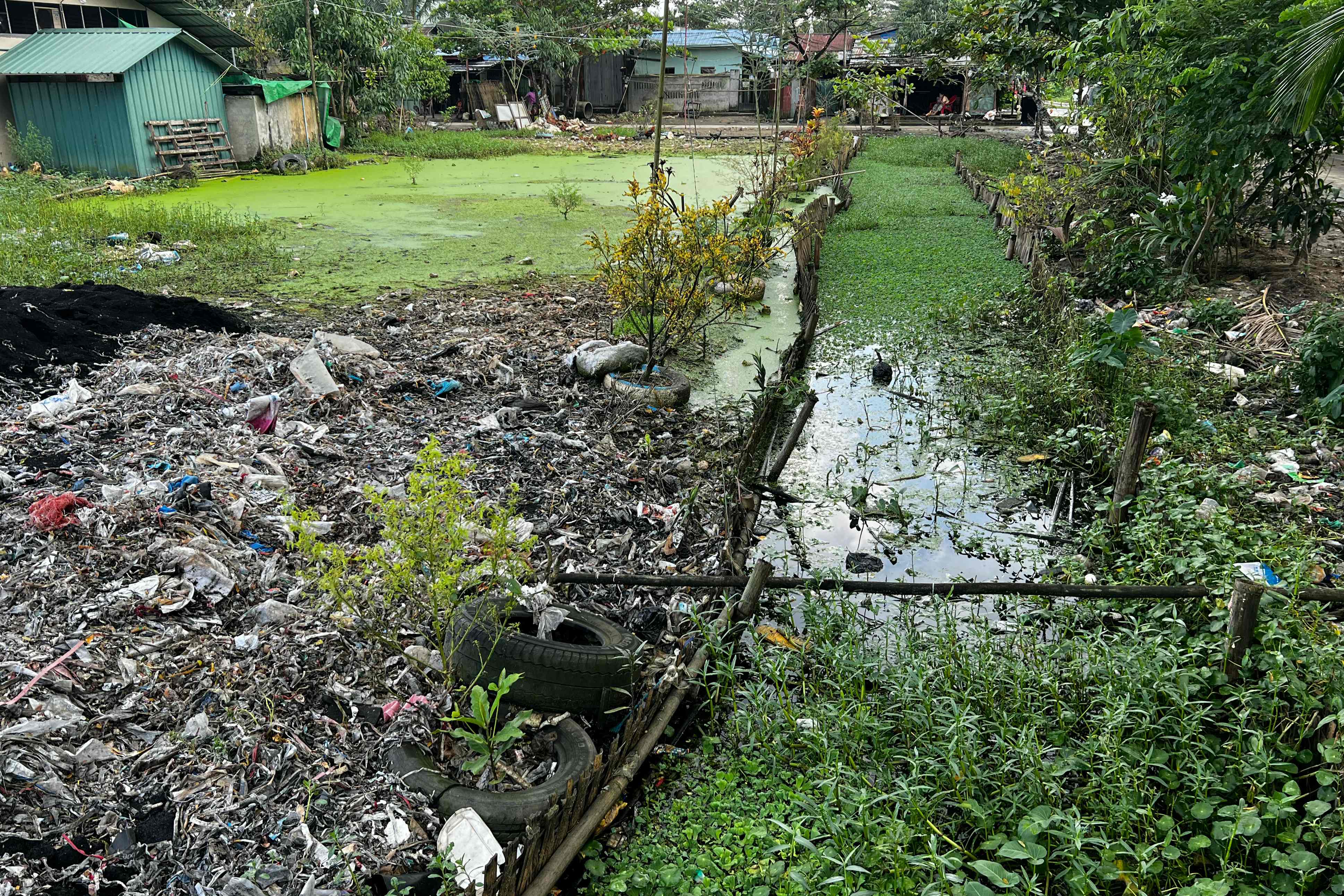 A photo, taken on October 11, 2023 shows plastic waste clogging waterways in Yangon’s Shwe Pyi Thar township. The build-up of plastic makes the water dark and dirty, residents said, and exacerbates monsoon flooding