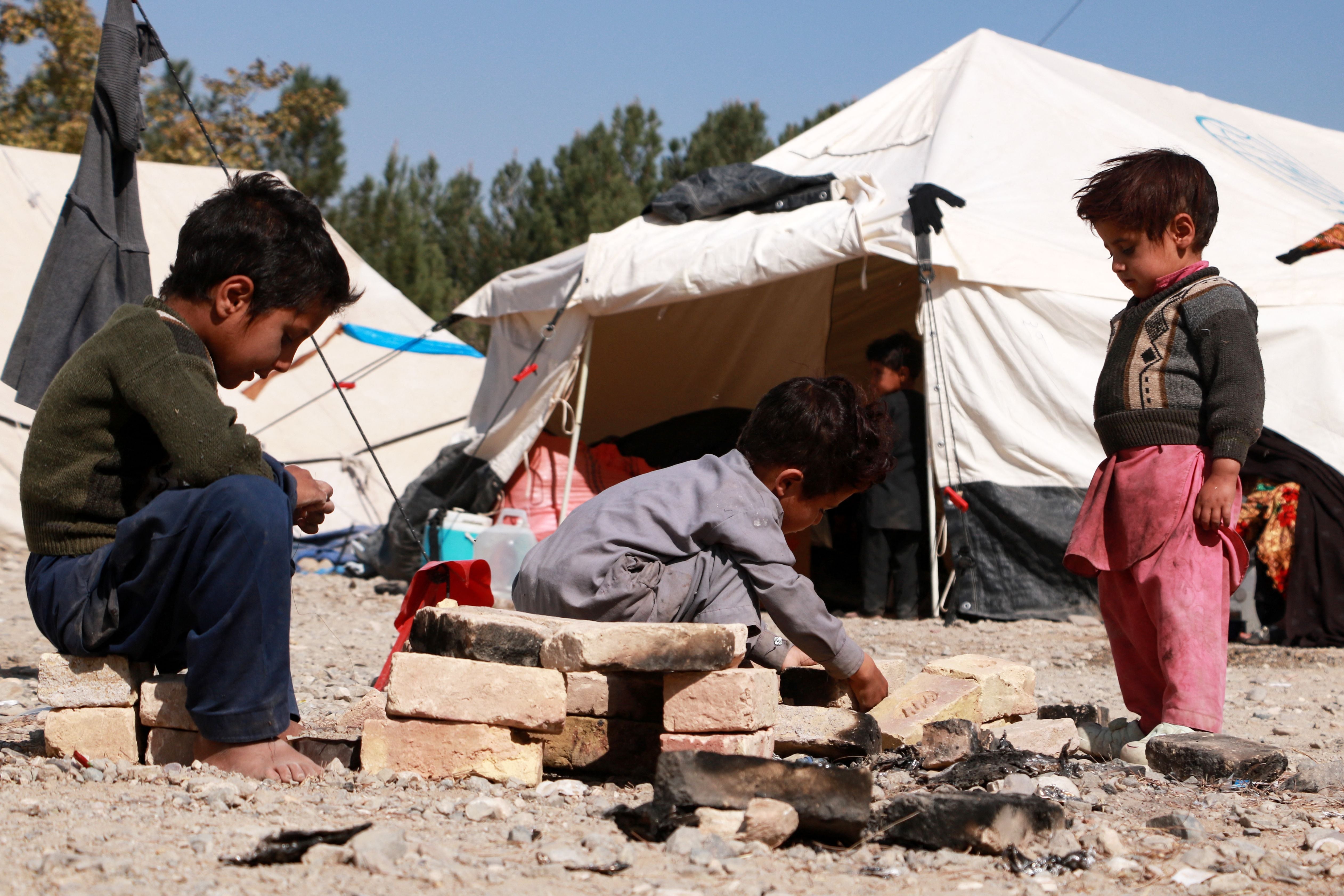 Afghan children play outside their makeshift shelters at a camp set-up after earthquake on the outskirts of Herat