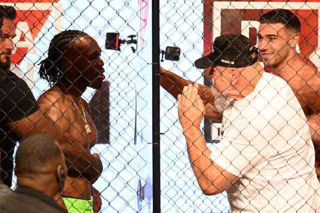 <p>John Fury, centre-right, punches the glass separating him from KSI </p>