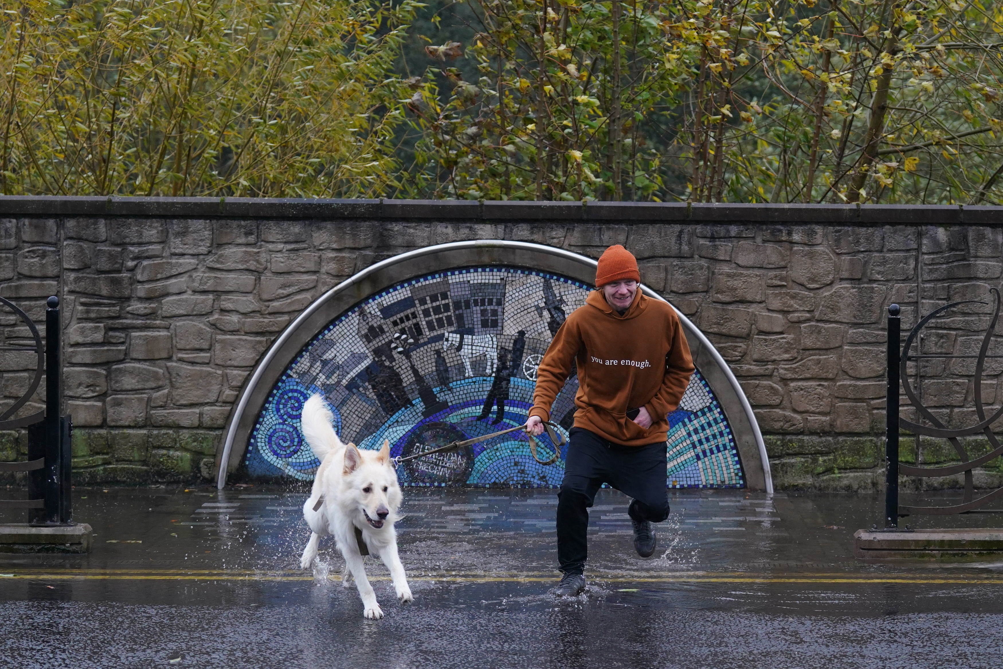 A man walking his dog jumps over a puddle on River Street, Brechin, wheren hundreds of residents have been told to evacuate