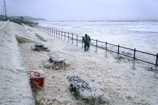 <p>A man walks through sea foam in Seaburn, Sunderland,  as Storm Babet batters the country</p>