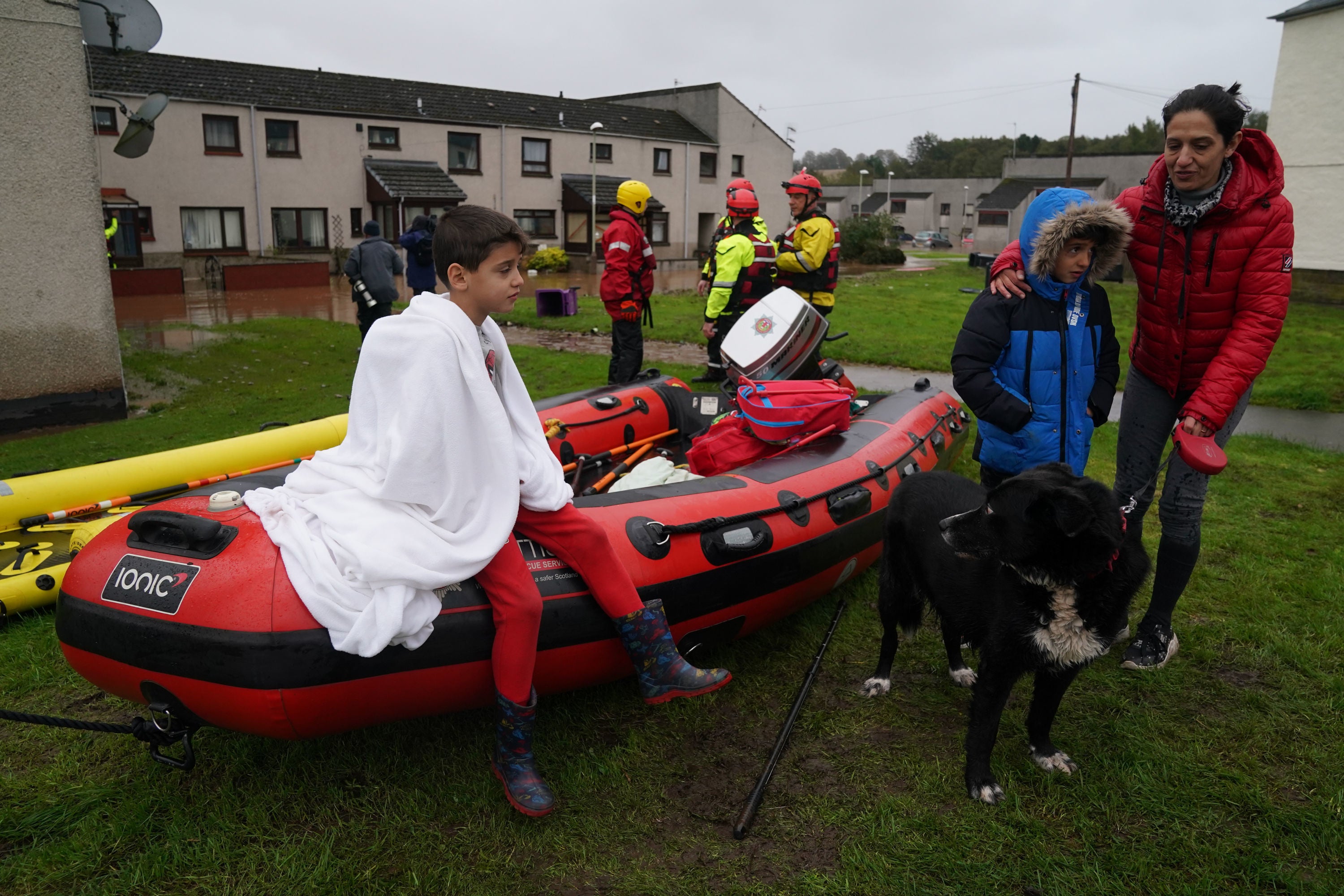 A boy sits on a rescue boat in Brechin, Scotland, which was flooded as torrential rain battered the town overnight