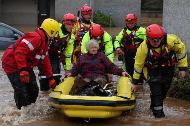 <p>An elderly lady is helped amid flooding in Brechin, Scotland</p>