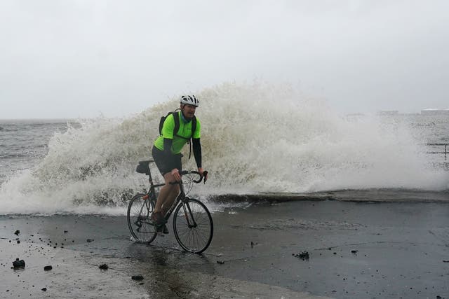 A man cycles along Clontarf promenade in Dublin as Ireland’s meteorological agency issued fresh weather warnings for intense rain (PA)