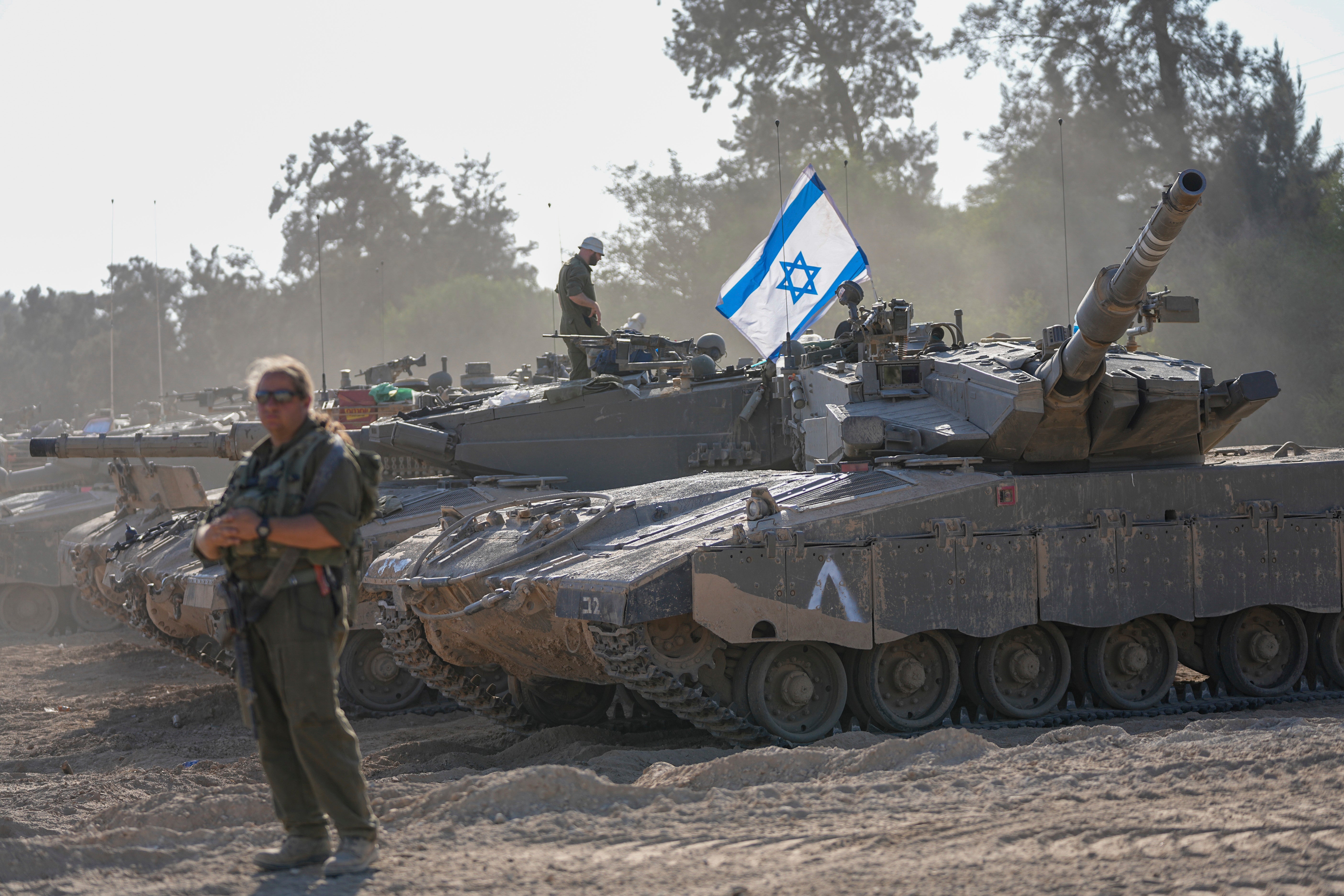 Israeli soldiers work on a tank at a staging area near the border with the Gaza Strip