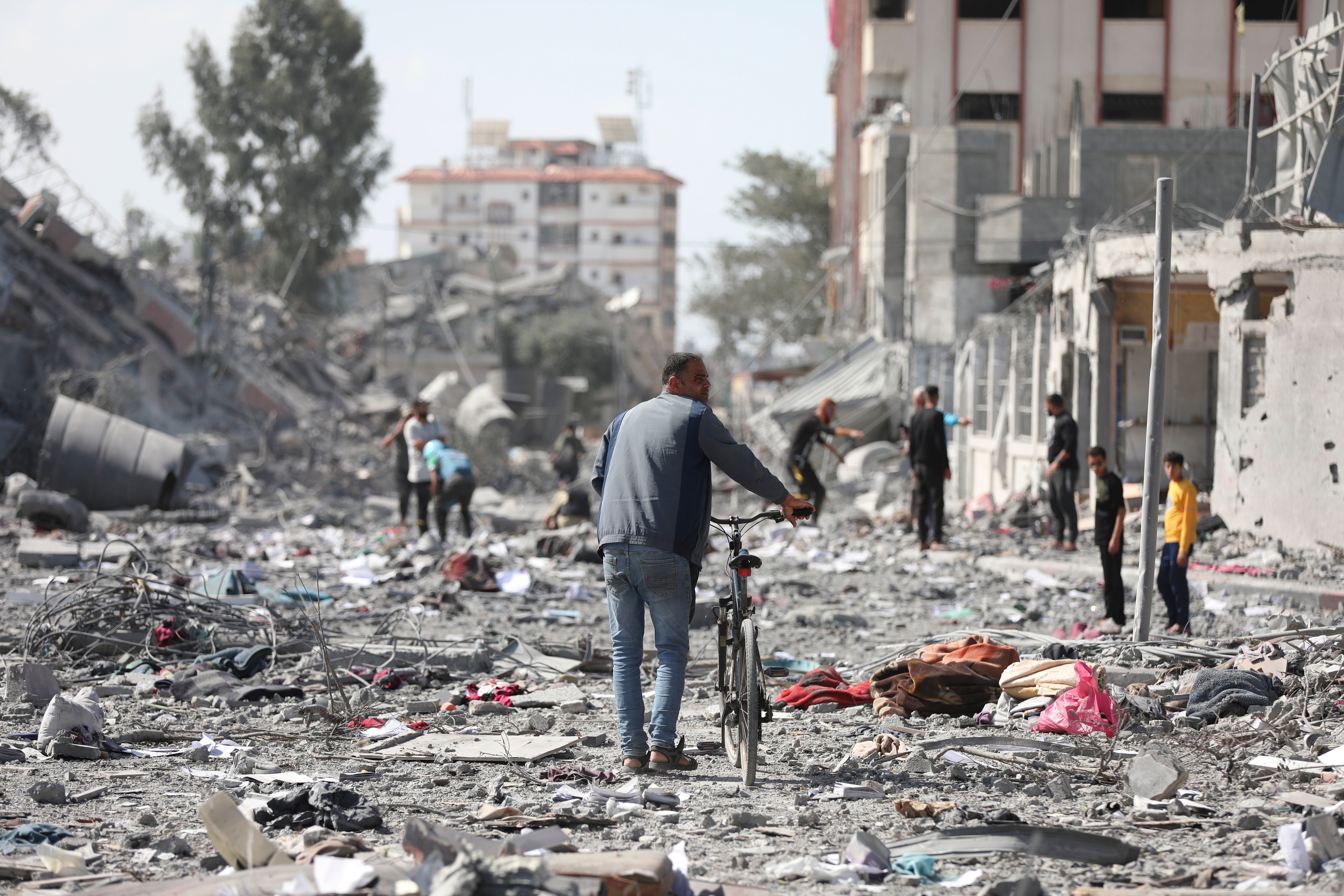 Palestinians walk by the buildings destroyed in the Israeli bombardment on al-Zahra, on the outskirts of Gaza City