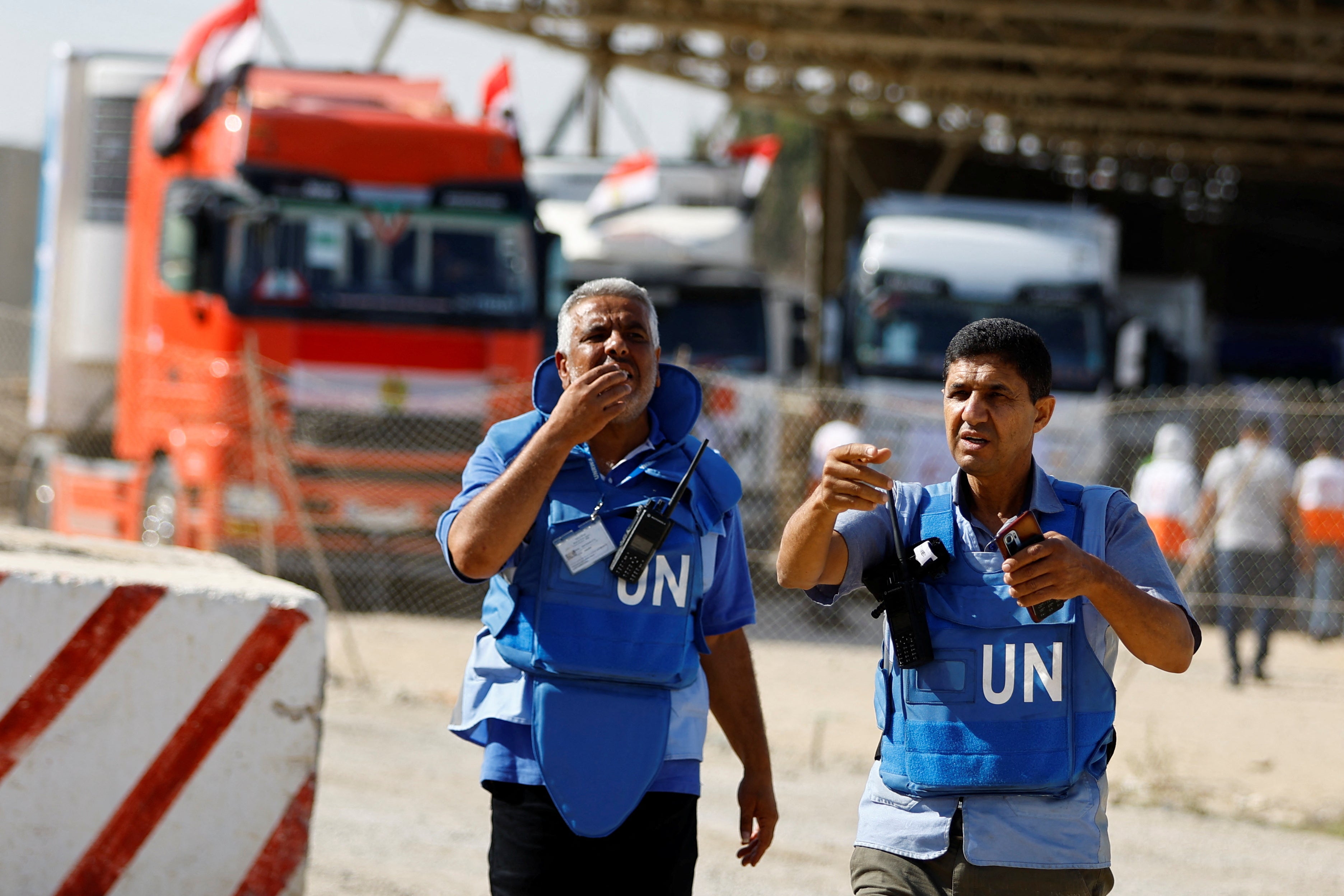 UN workers as trucks carrying aid arrive at the Palestinian side of the border with Egypt