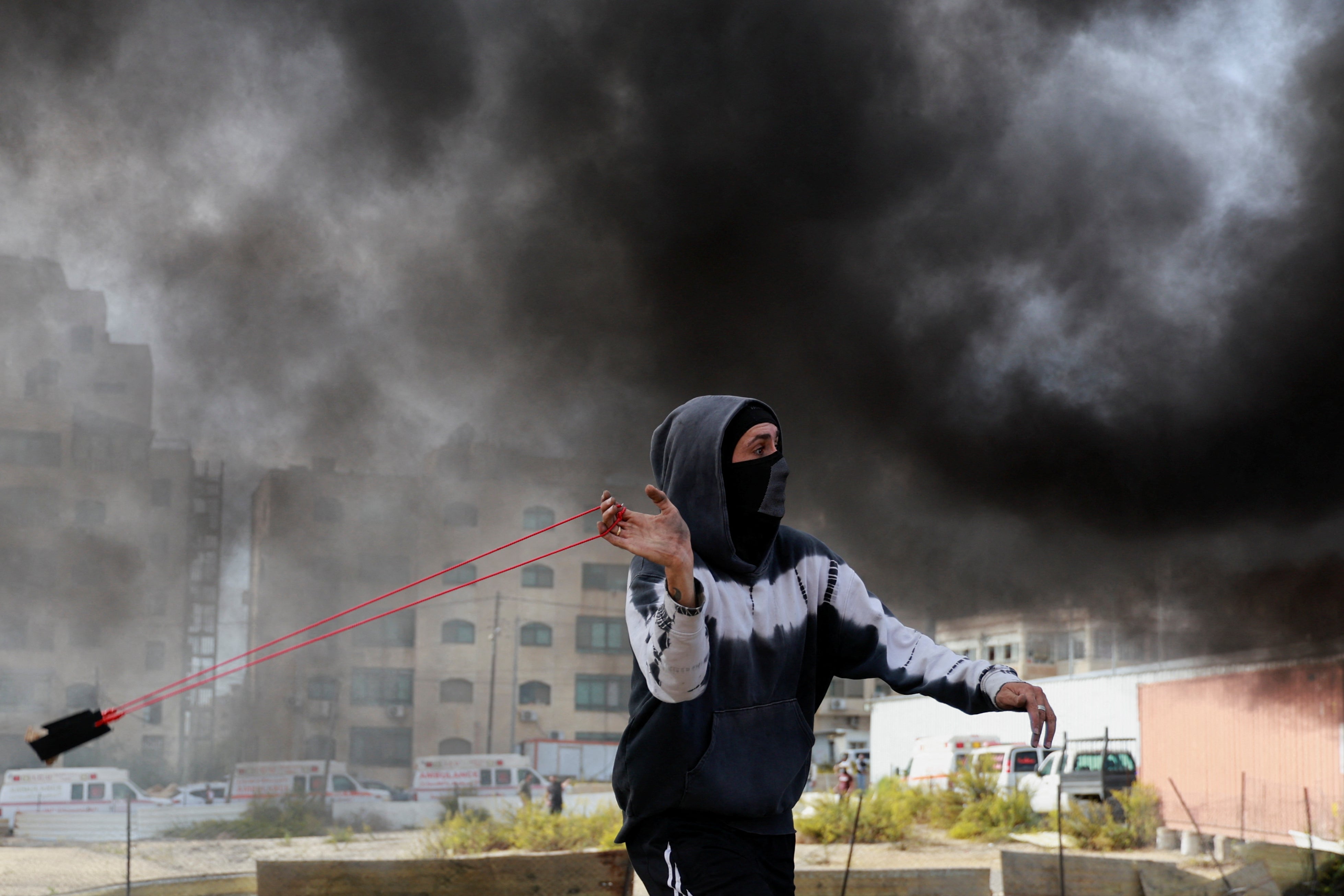 A Palestinian uses a sling to hurl stones during clashes with Israeli forces near Ramallah