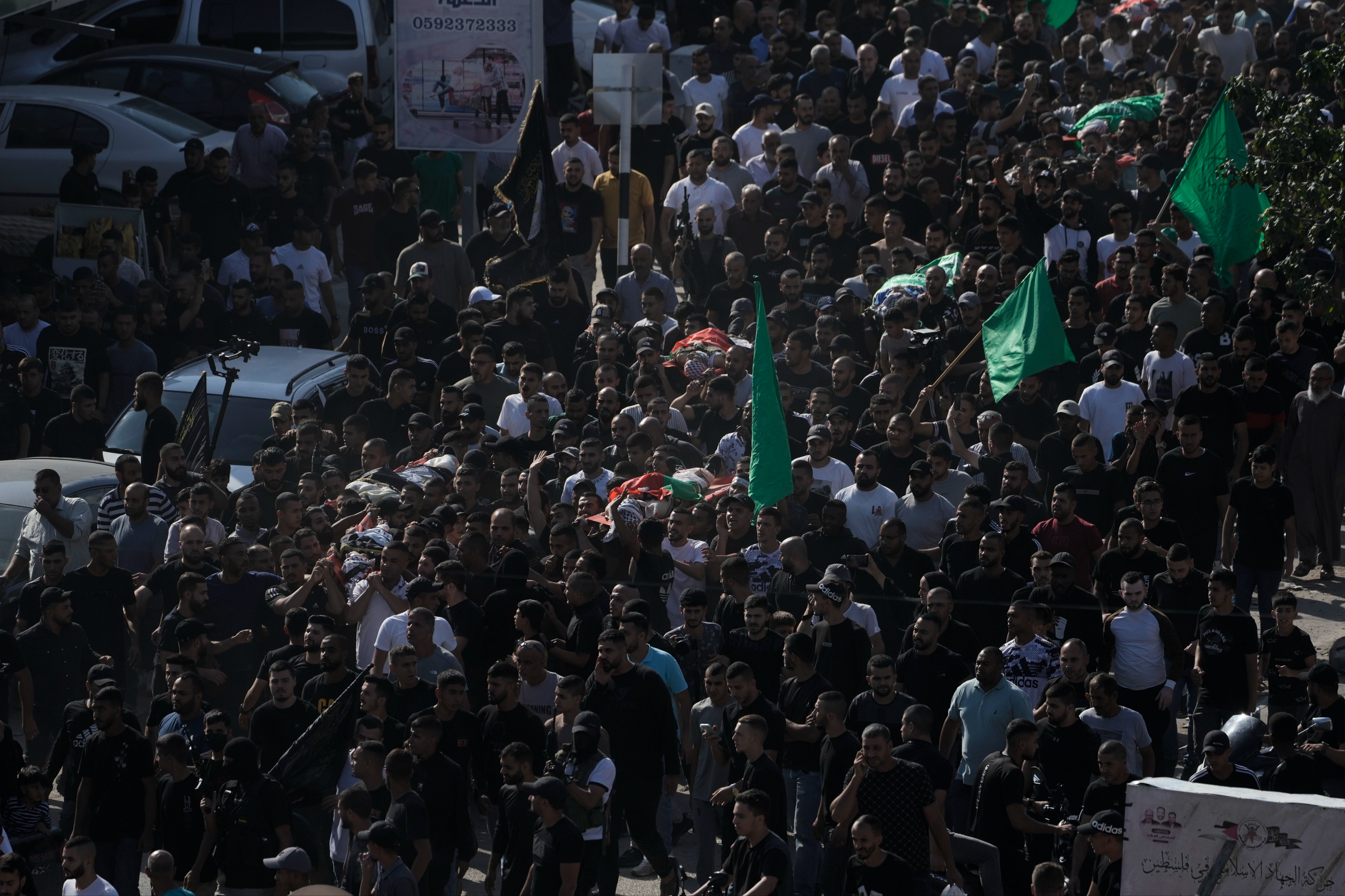 Flags and banners of Hamas and Islamic Jihad fly at the funeral of those slain at Nur Sham