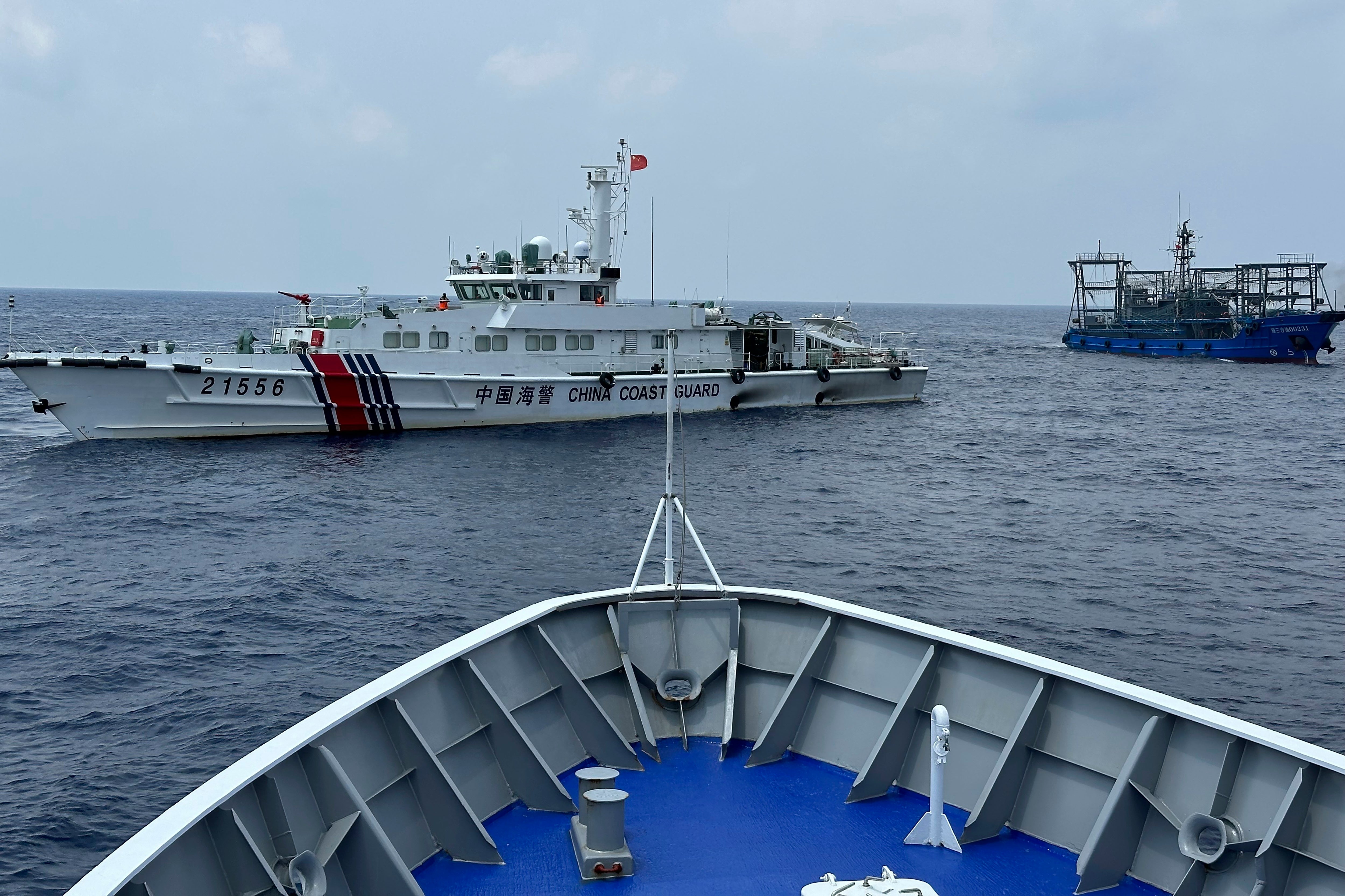 A Chinese coast guard ship, left, with a Chinese militia vessel, right, blocks Philippine coast guard ship, ‘BRP Sindangan’, as it tried to head towards Second Thomas Shoal at the disputed South China Sea during rotation and resupply mission