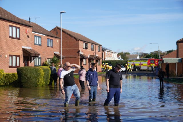 <p>Residents walk through flood water in Retford in Nottinghamshire, after Storm Babet battered the UK</p>