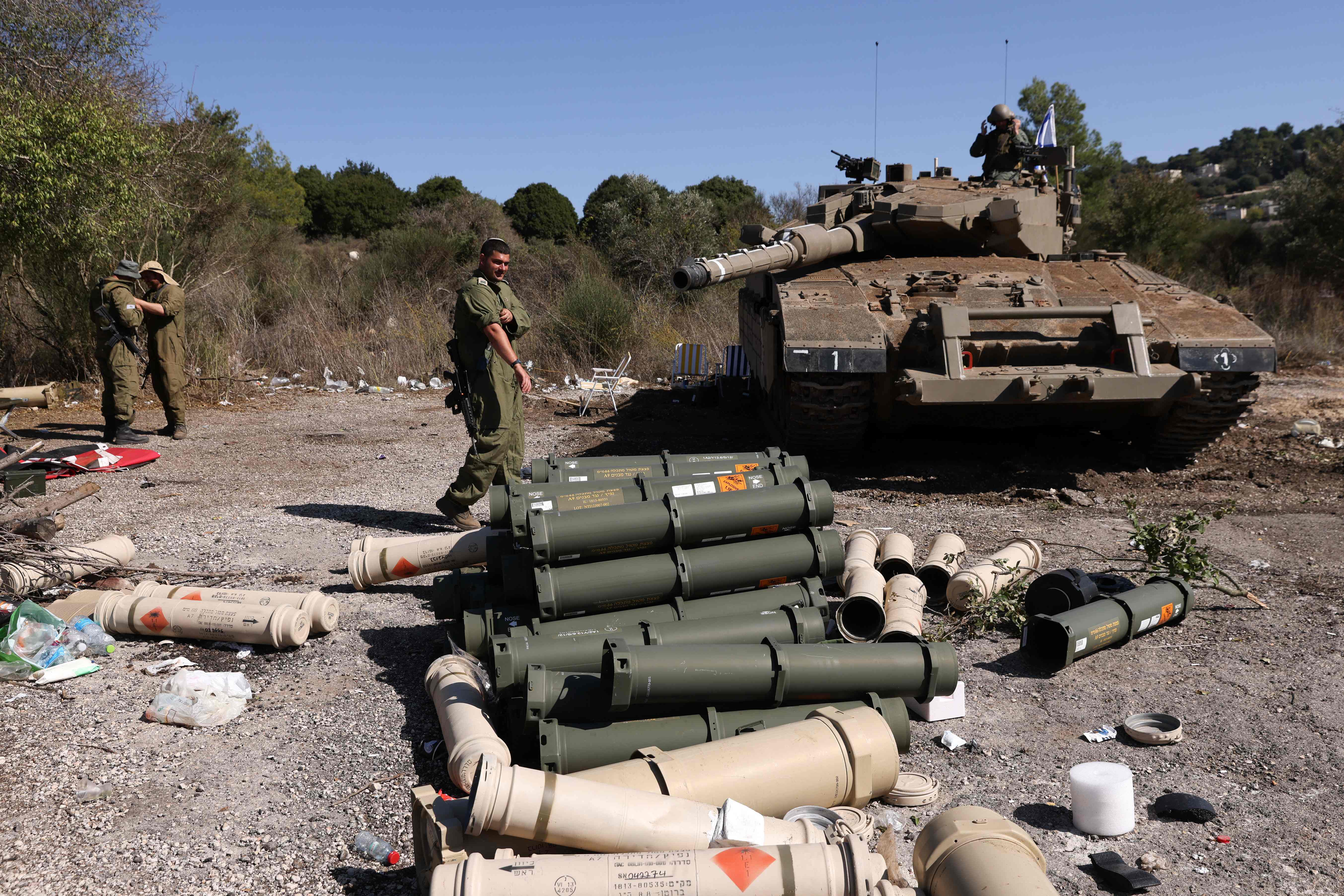 Israeli soldiers stand near a Merkava tank as they man a position at an undisclosed location on the border with Lebanon