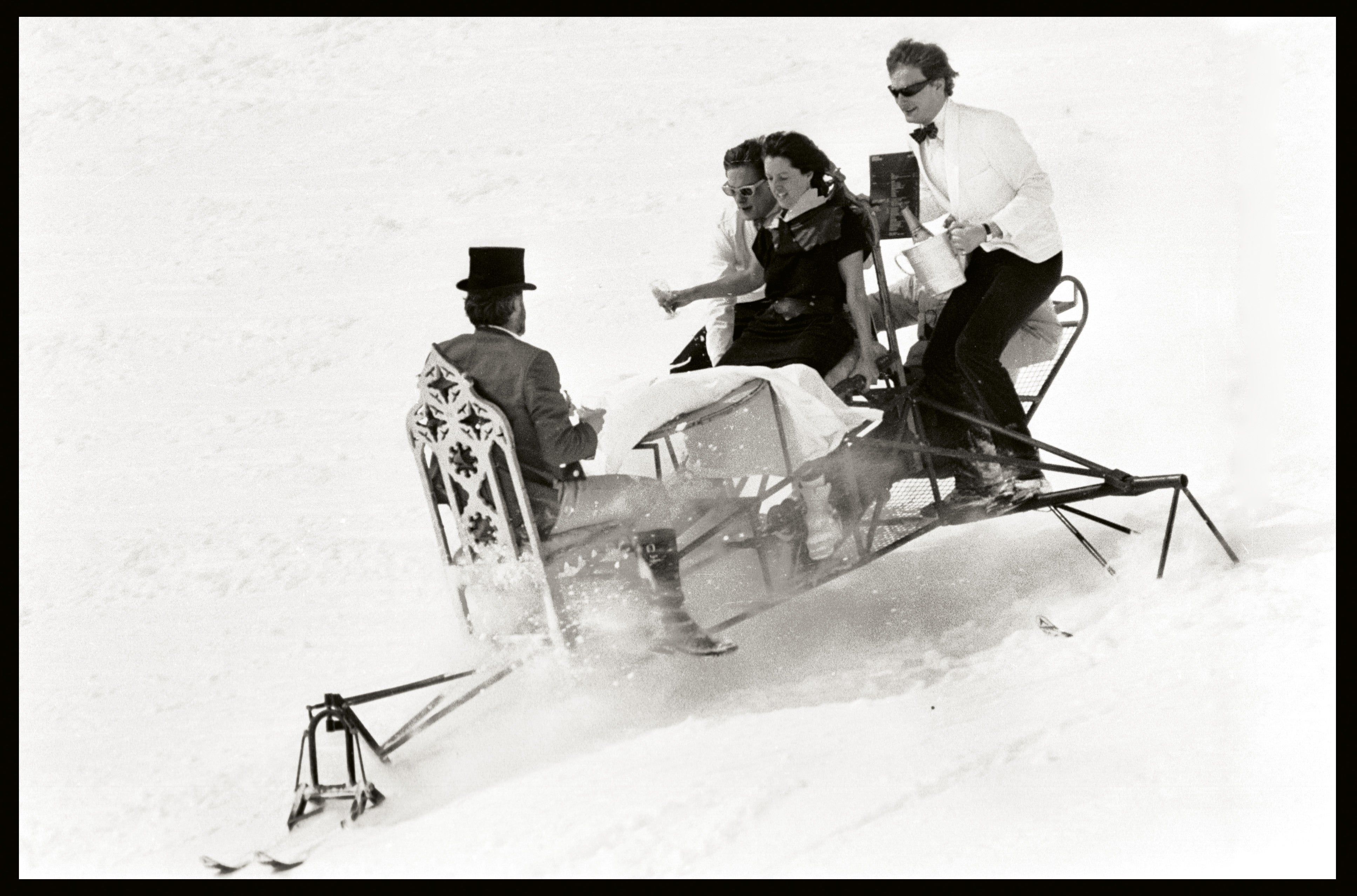 David Kirke, Tim Hunt, Nicky Slade and Lord Xan Rufus Isaacs going down the Saint Moritz slopes on a dining table