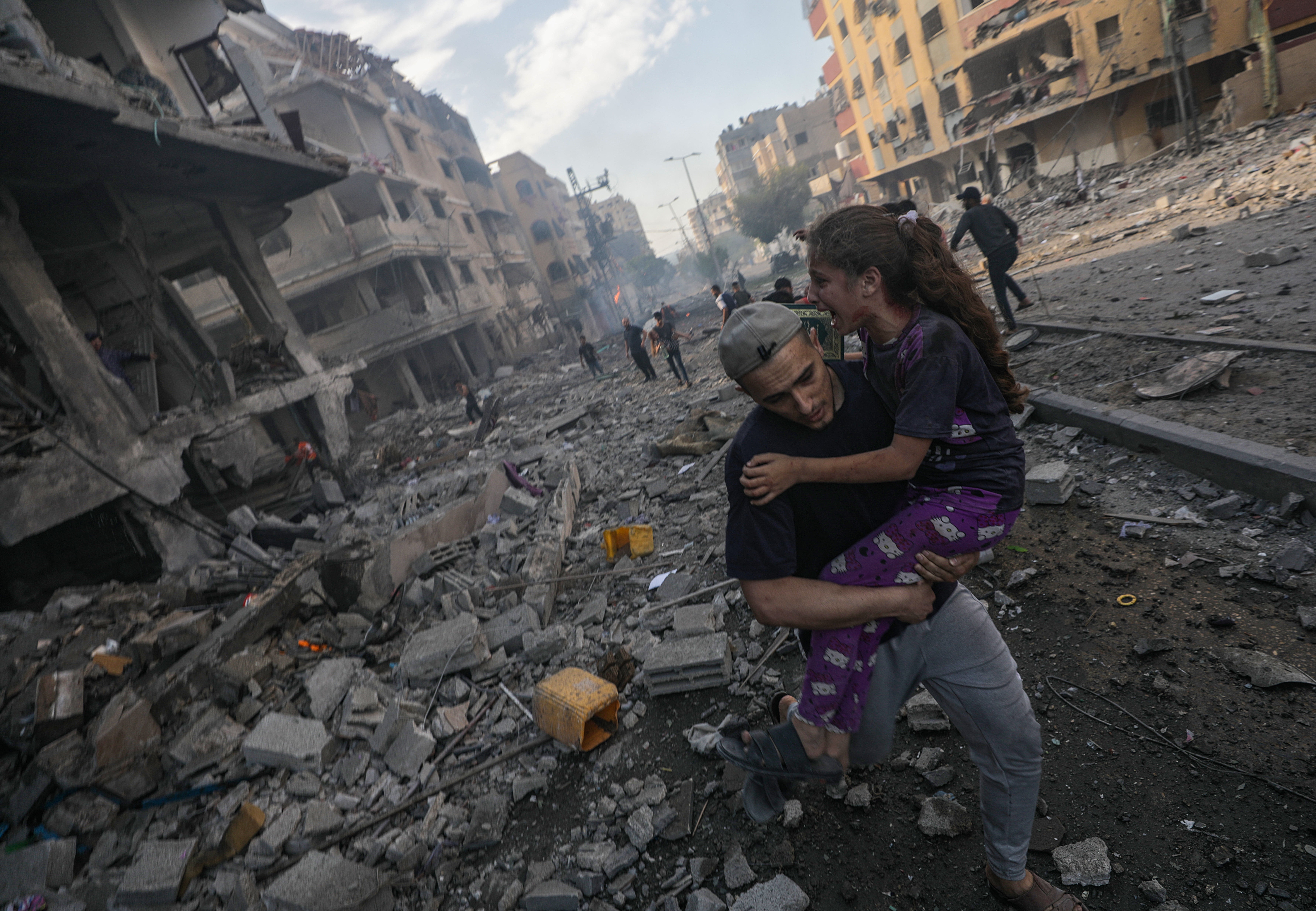 A man carries a wounded girl following an airstrike in Gaza on 21 October.