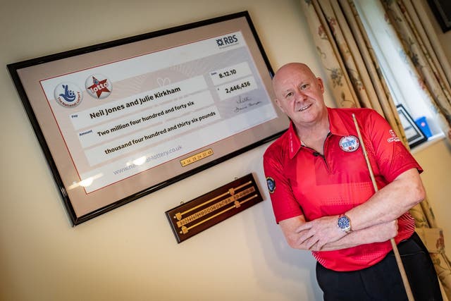 Neil Jones, pictured with his framed Lottery cheque and his winning numbers at home in Stoke-on-Trent (National Lottery/PA)