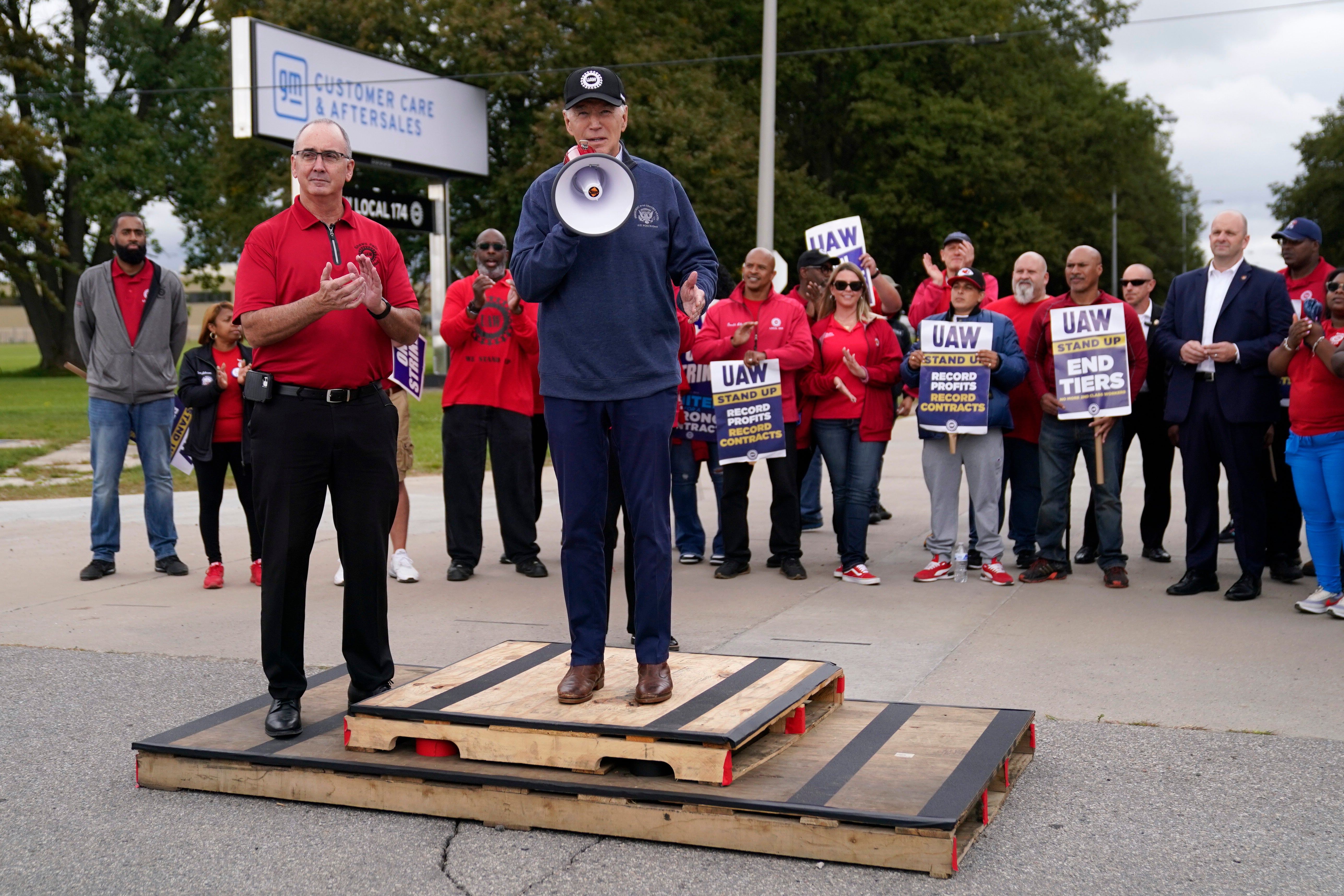 United Auto Workers president Shawn Fain, left, listens as President Joe Biden speaks to striking UAW members outside a General Motors facility on 26 September, 2023, in Van Buren Township, Michigan