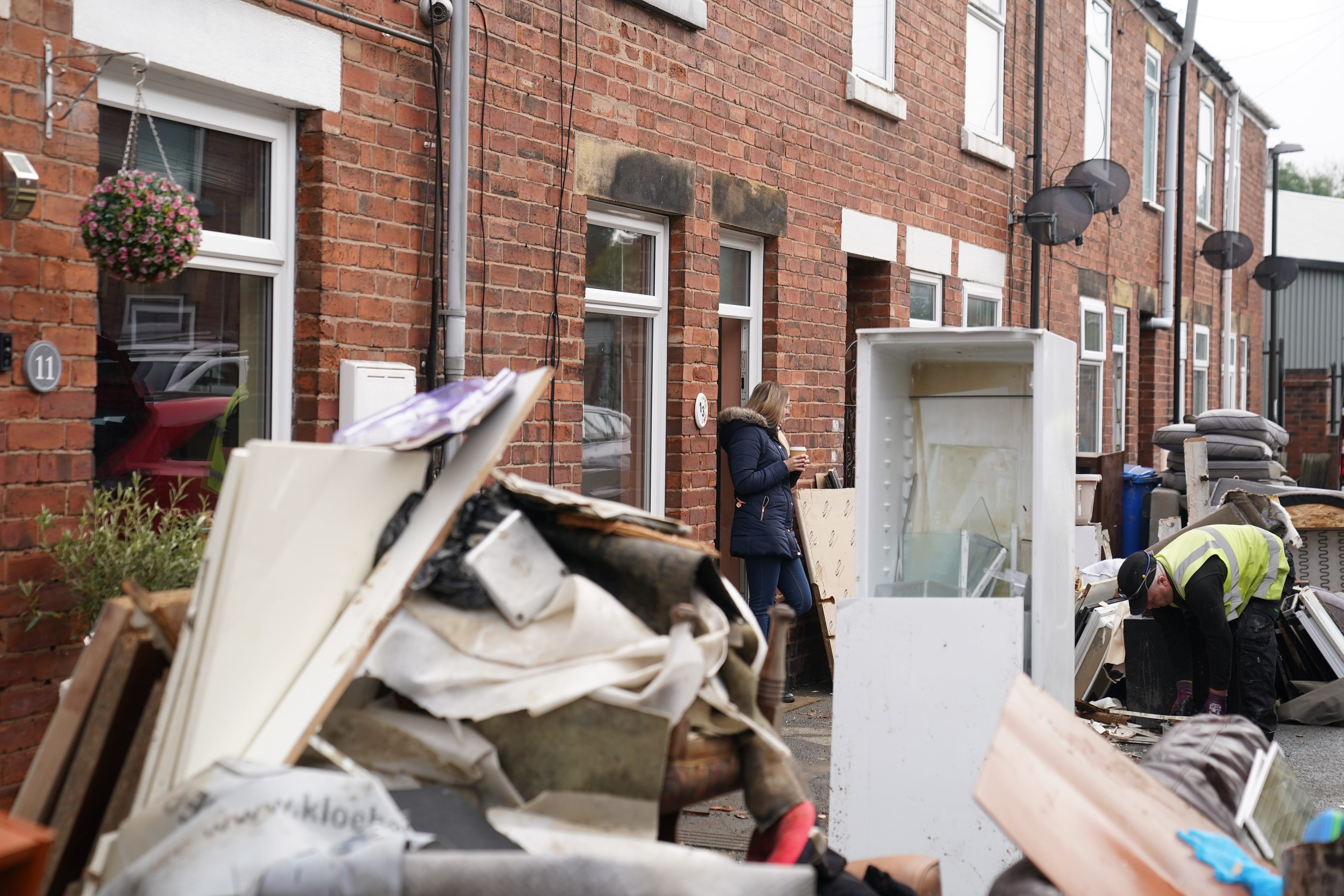 <p>A resident looks at a local authority worker collecting damaged furniture from outside a property on Sherwood Street in Chesterfield, as the clean up began in the aftermath of Storm Babet</p>