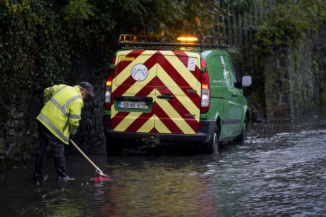 A local authority worker clears a road gully in Co. Kilkenny (Niall Carson/PA)