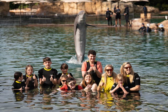 Children swim with dolphins during the Dreamflight visit to Discovery Cove in Orlando, Florida (James Manning/PA)