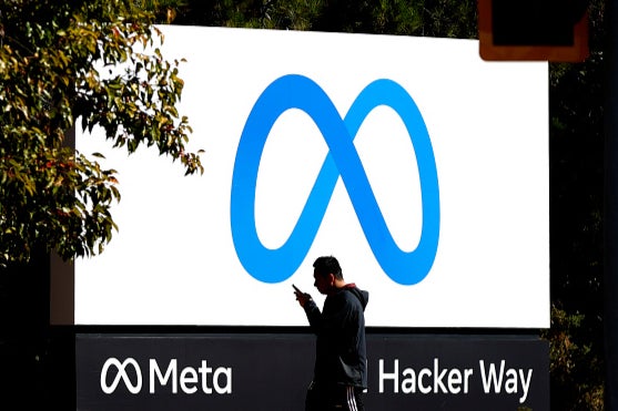 A pedestrian walks in front of a new logo and the name 'Meta' on the sign in front of Facebook headquarters on October 28, 2021