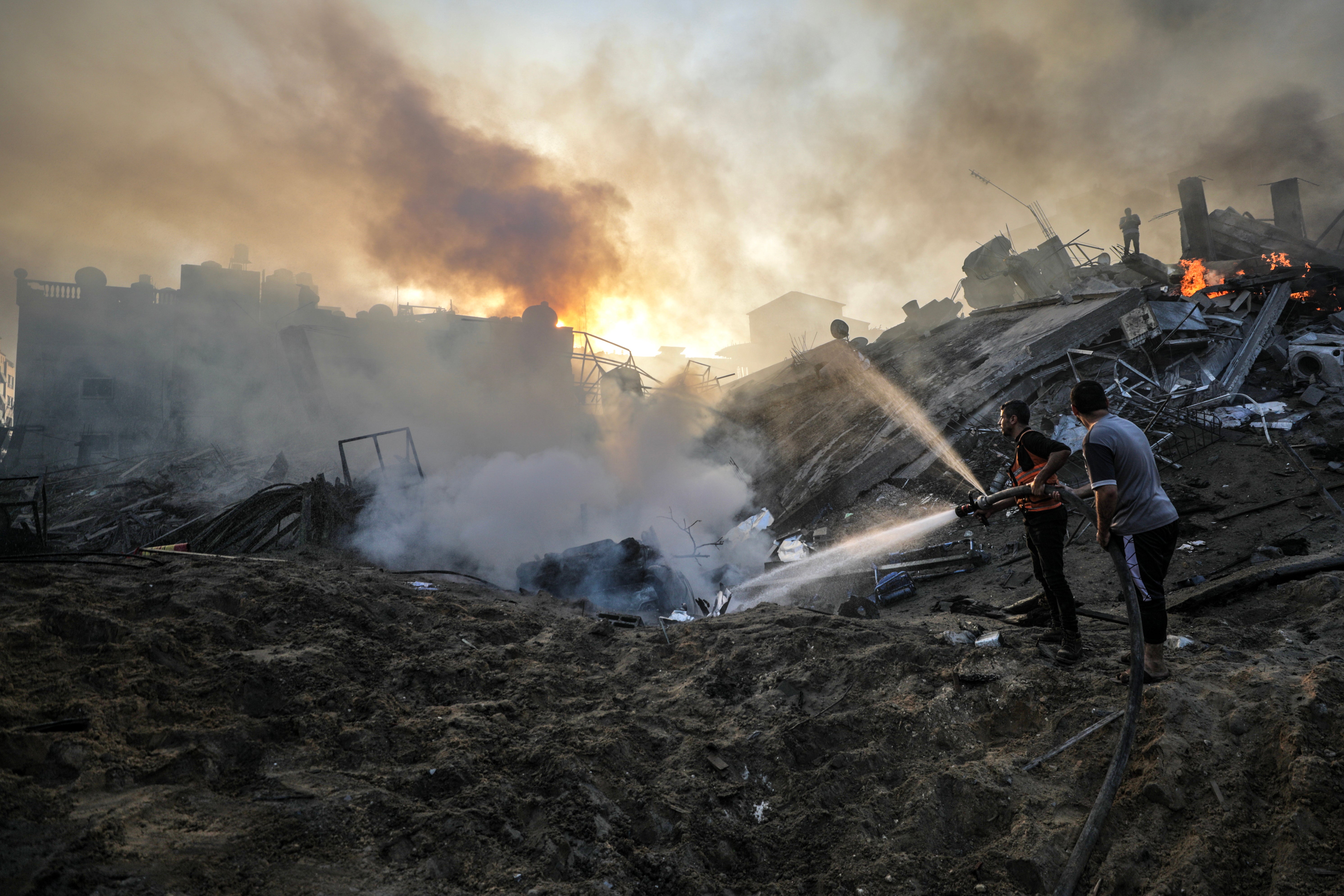 Palestinians try to put out a fire at a destroyed area following Israeli air strikes in Gaza City