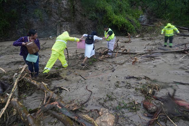 <p>People are helped across a highway blocked by a landslide following Hurricane Otis near Acapulco, Mexico on Wednesday, October 25, 2023</p>