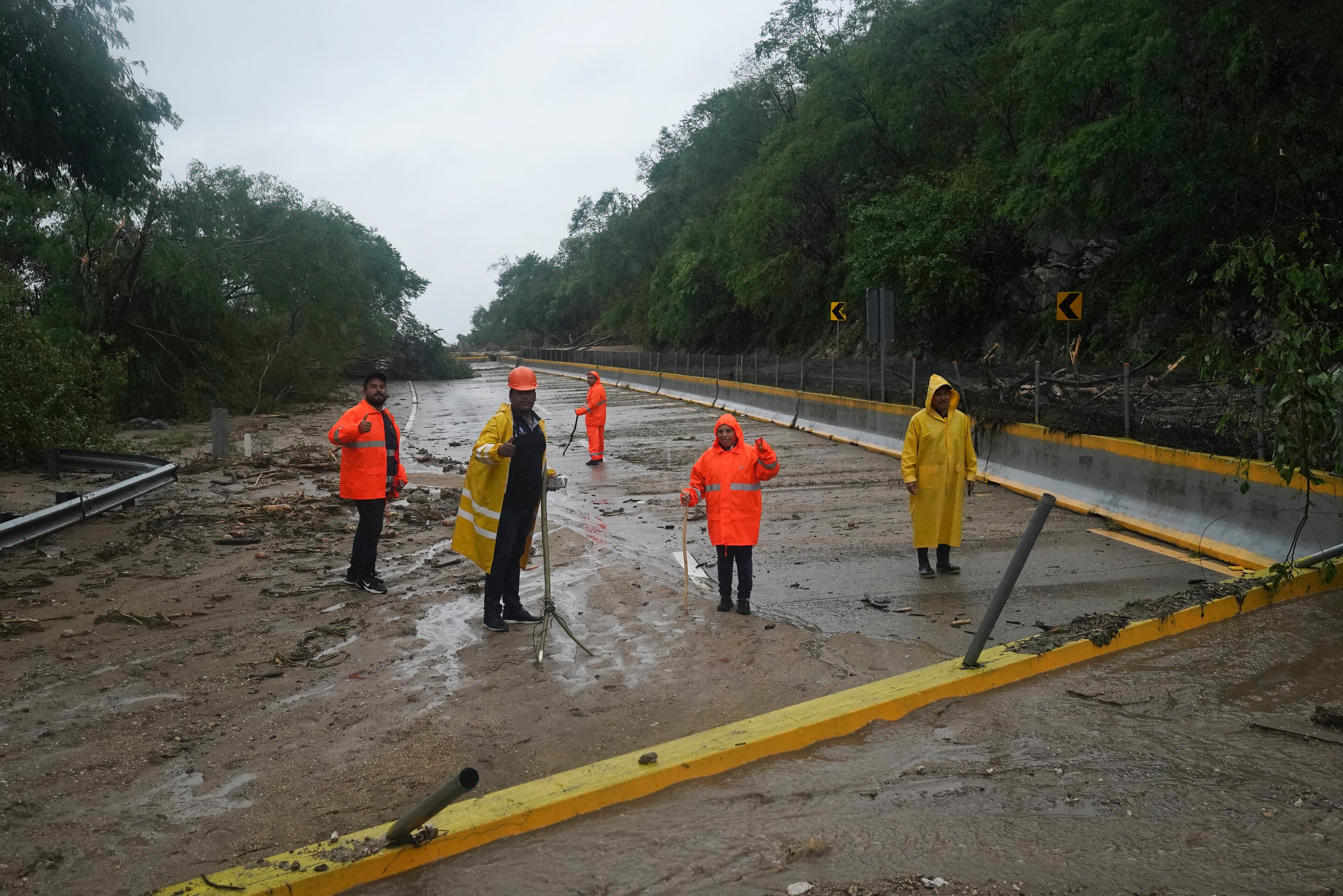Workers clear a blocked highway after the passing of Hurricane Otis near Acapulco, Mexico, Wednesday, Oct. 25, 2023