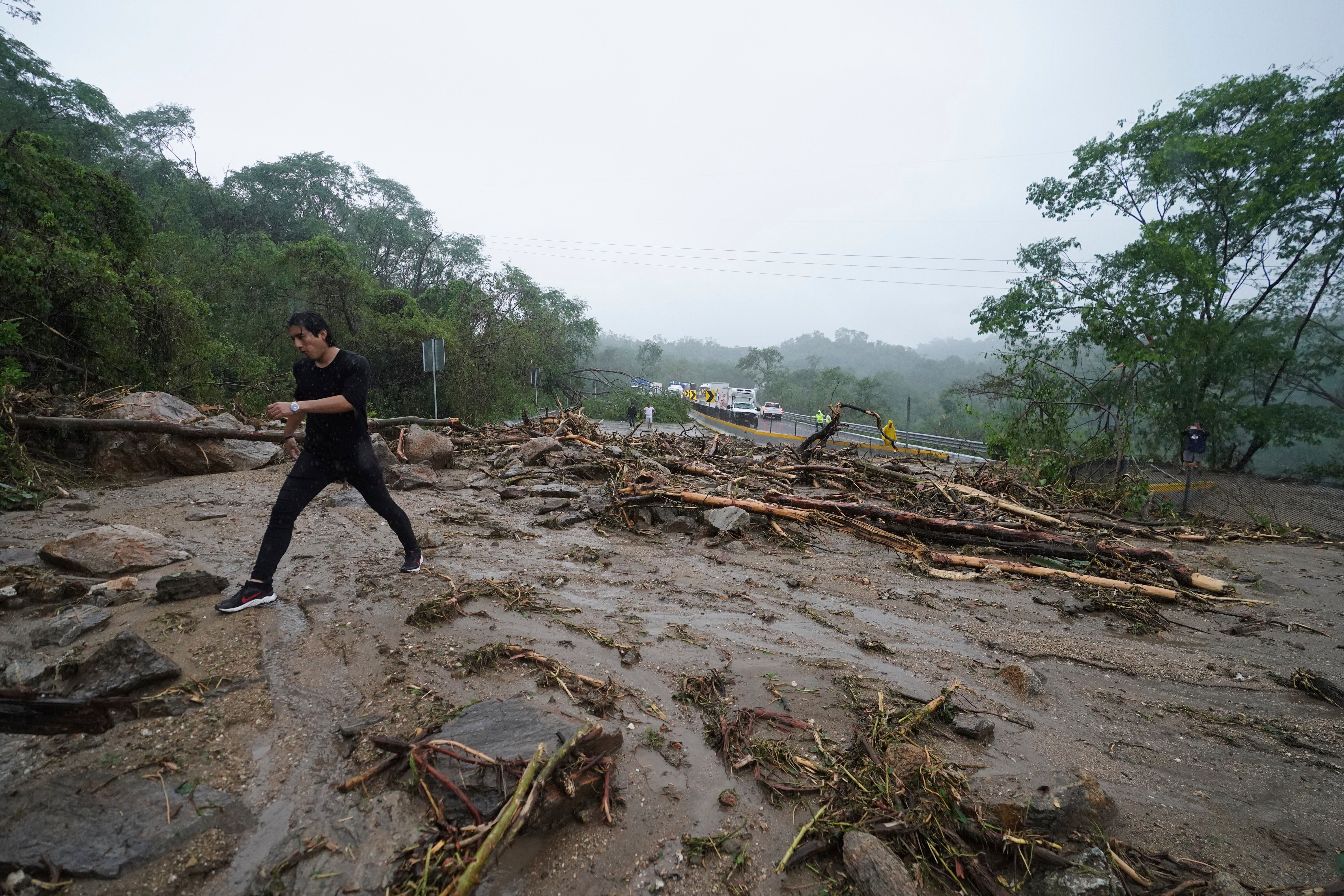 A man crosses a highway blocked by a landslide triggered by Hurricane Otis near Acapulco, Mexico, Wednesday, Oct. 25, 2023