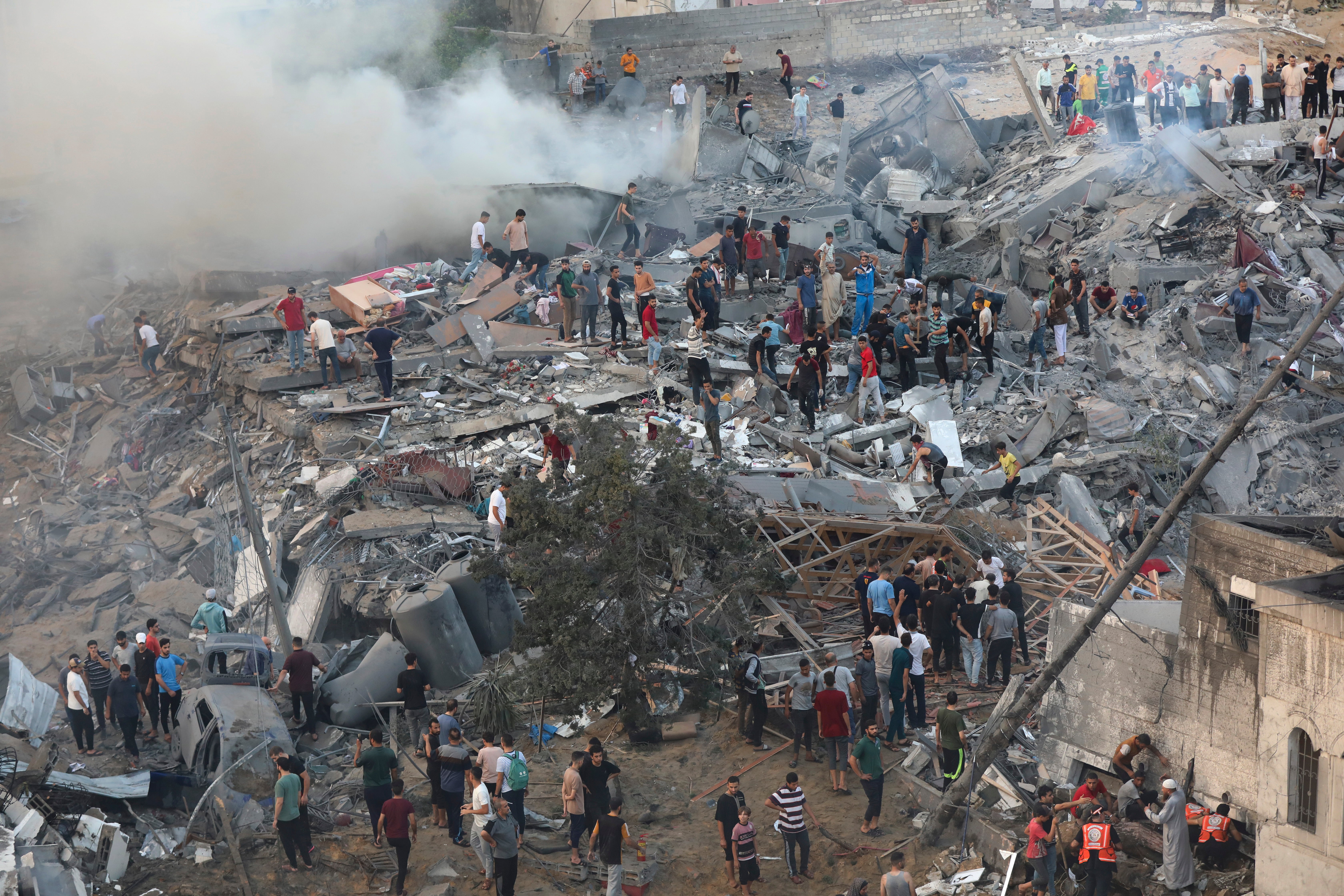 Palestinians inspect the damage of destroyed buildings following Israeli airstrikes on Gaza City,