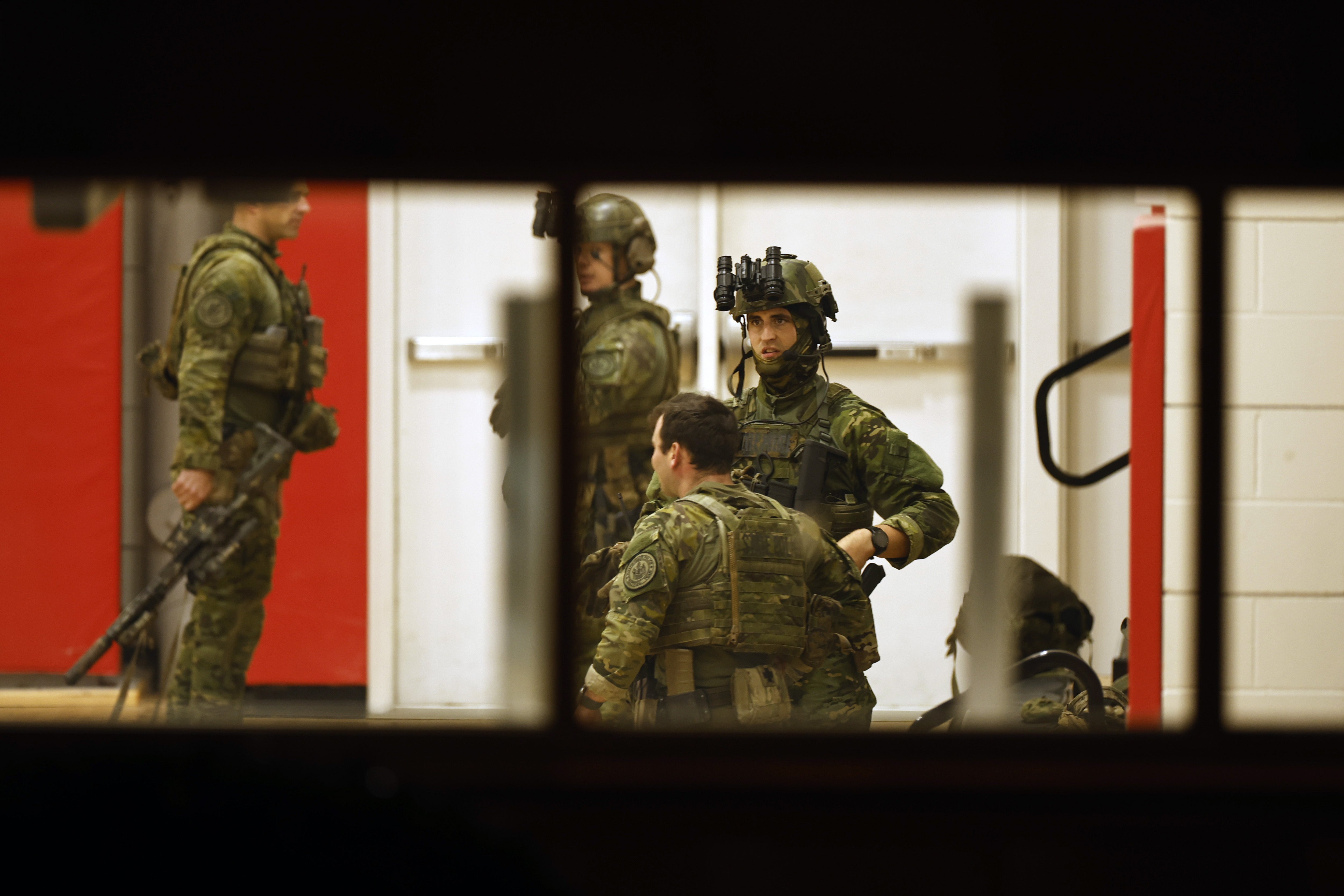 Police officers in tactical gear get ready in the Lisbon High School gymnasium amid active search for gunman