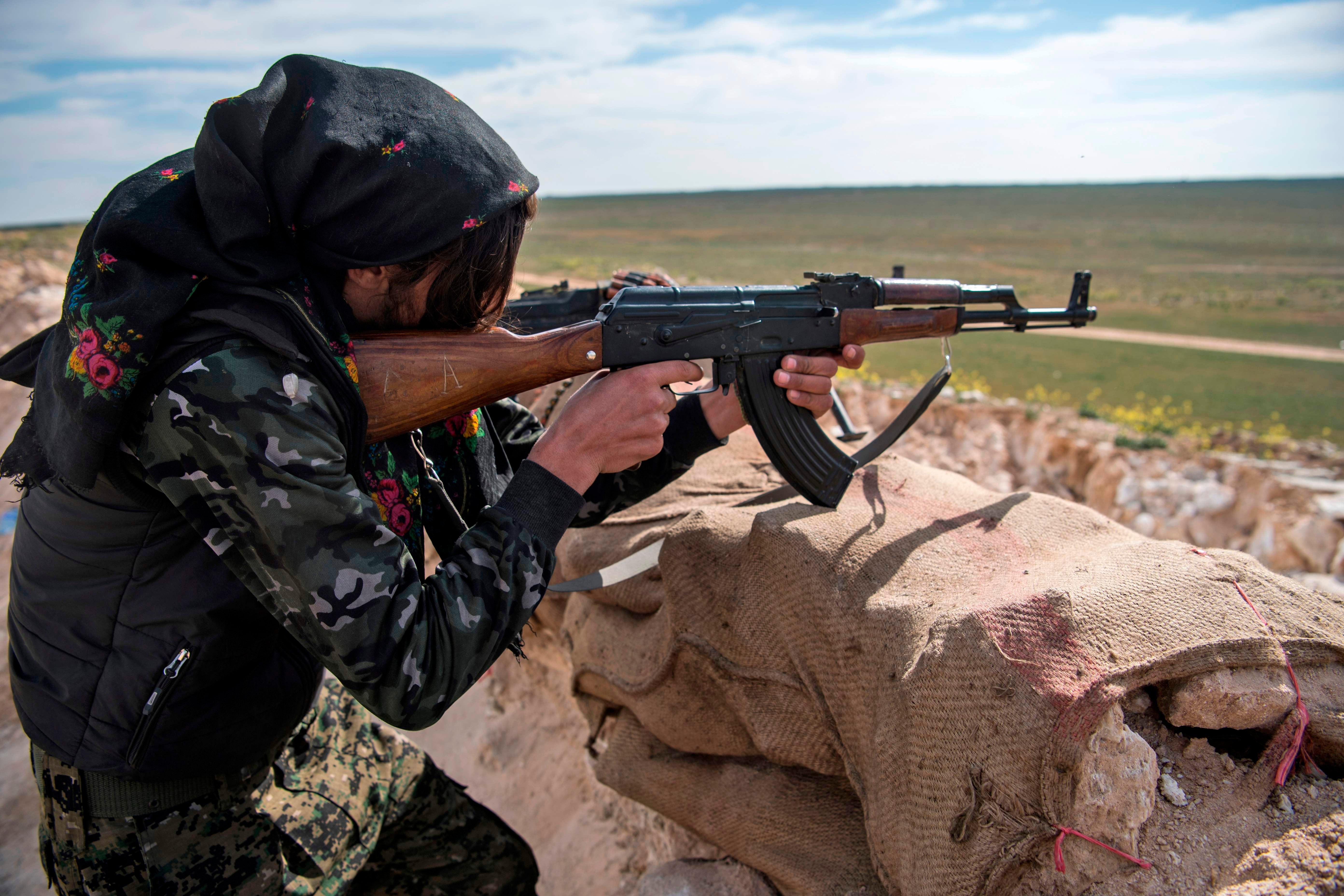 A female fighter with the US-backed Syrian Democratic Forces (SDF) takes aim during an operation to expel Islamic State from the Baghouz area in eastern Syria, February 2019