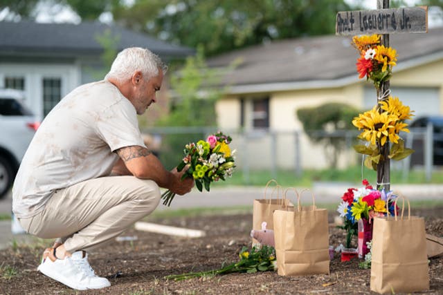 <p>A man in Jacksonville, Florida leaves flowers at a memorial for victims of a mass shooting in August </p>