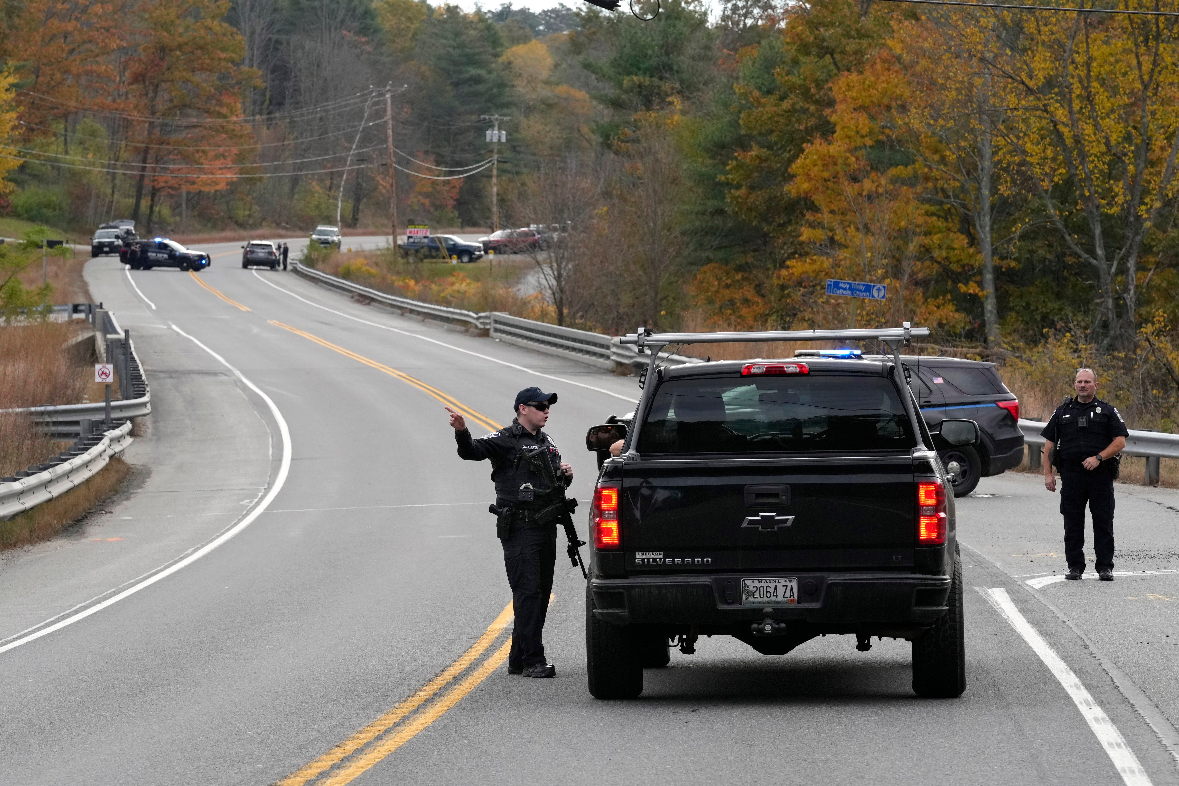 Police officers speak with a motorist at a roadblock in Lisbon, Maine
