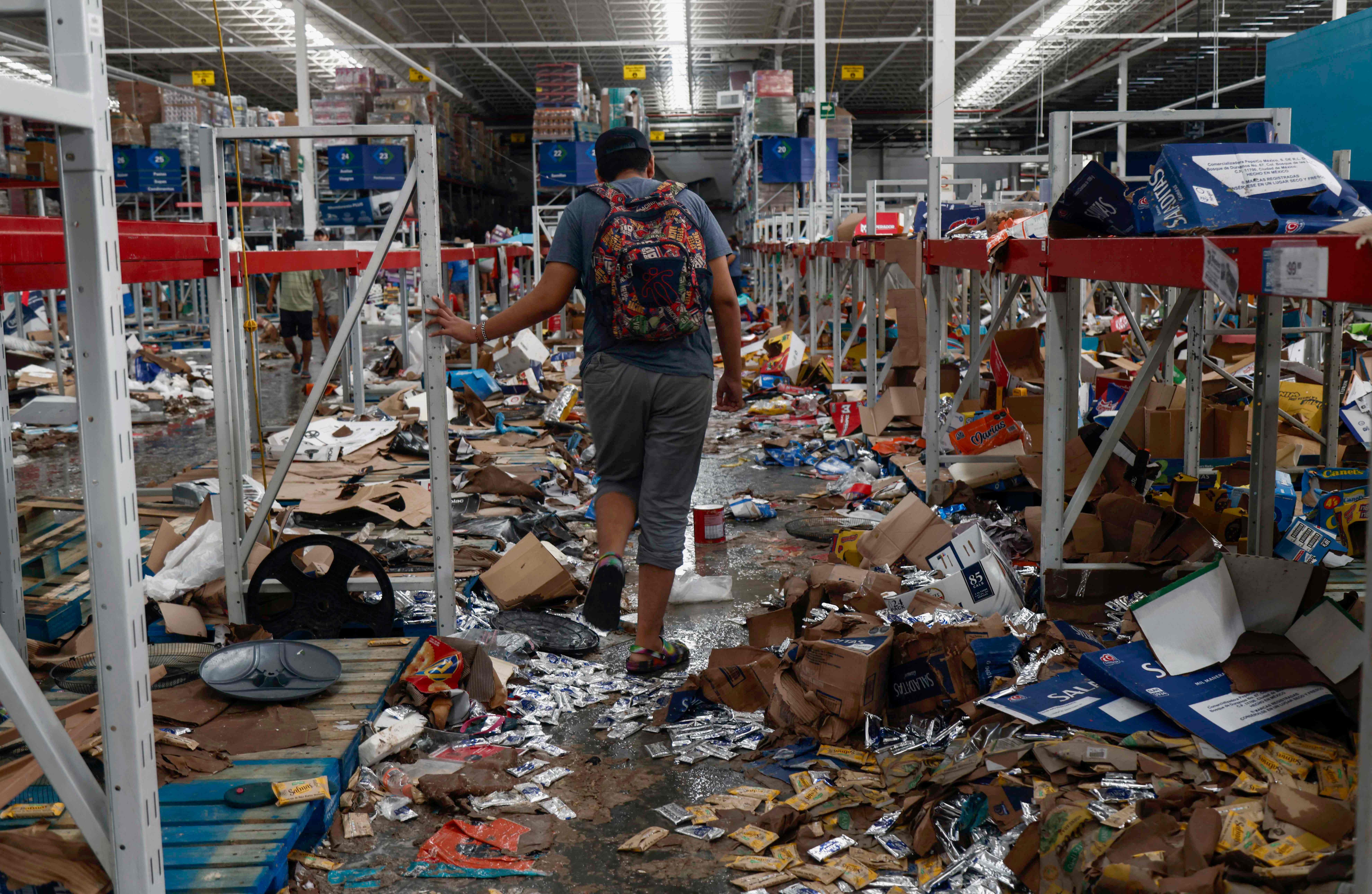A man walks on a looted supermarket after the passage of Hurricane Otis