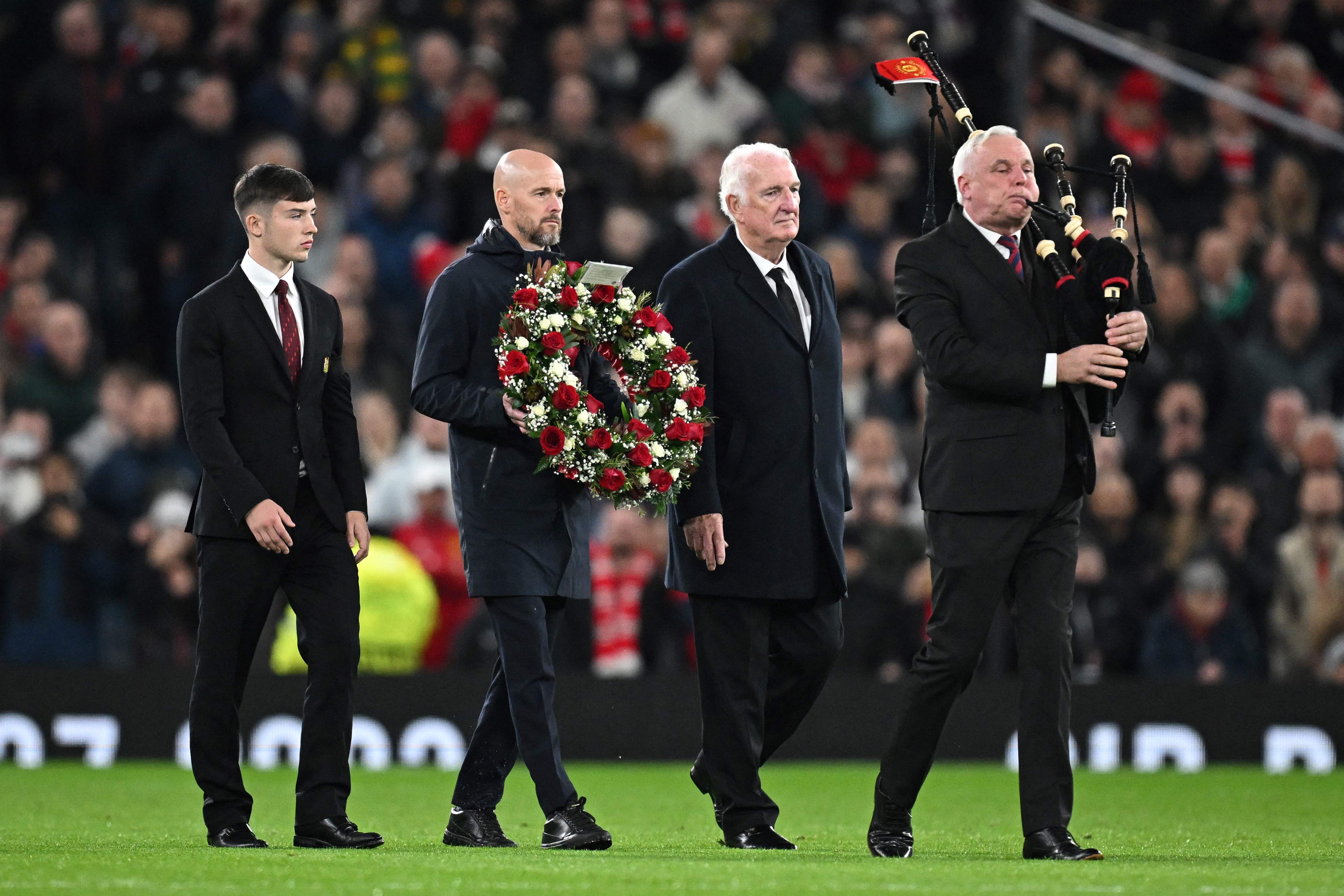 Erik ten Hag carries a wreath of flowers next to Alex Stepney and Dan Gore during a tribute to late Bobby Charlton