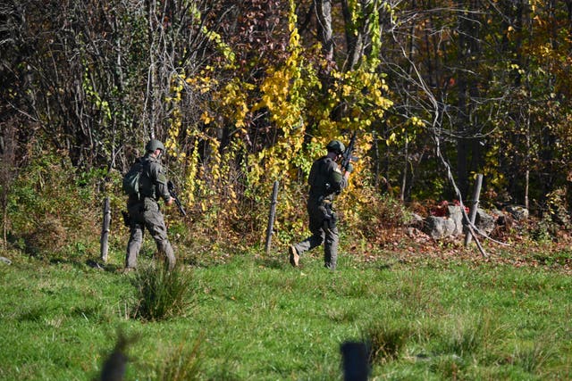 <p>Law enforcement personnel search a wooded area in Monmouth, Maine, amid the search for shooting suspect Robert Card</p>