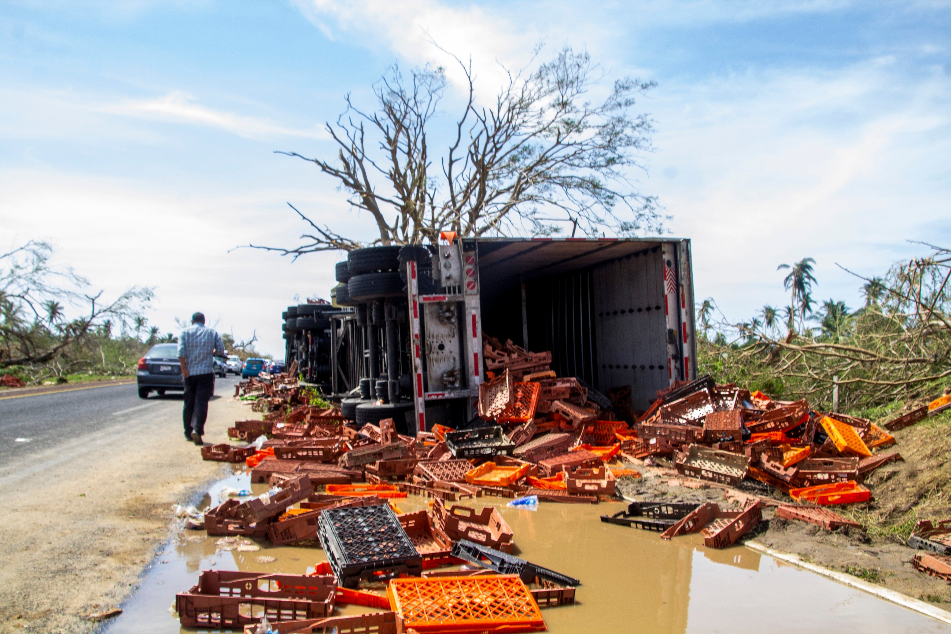 A damaged truck lies on the side of a road after hurricane Otis