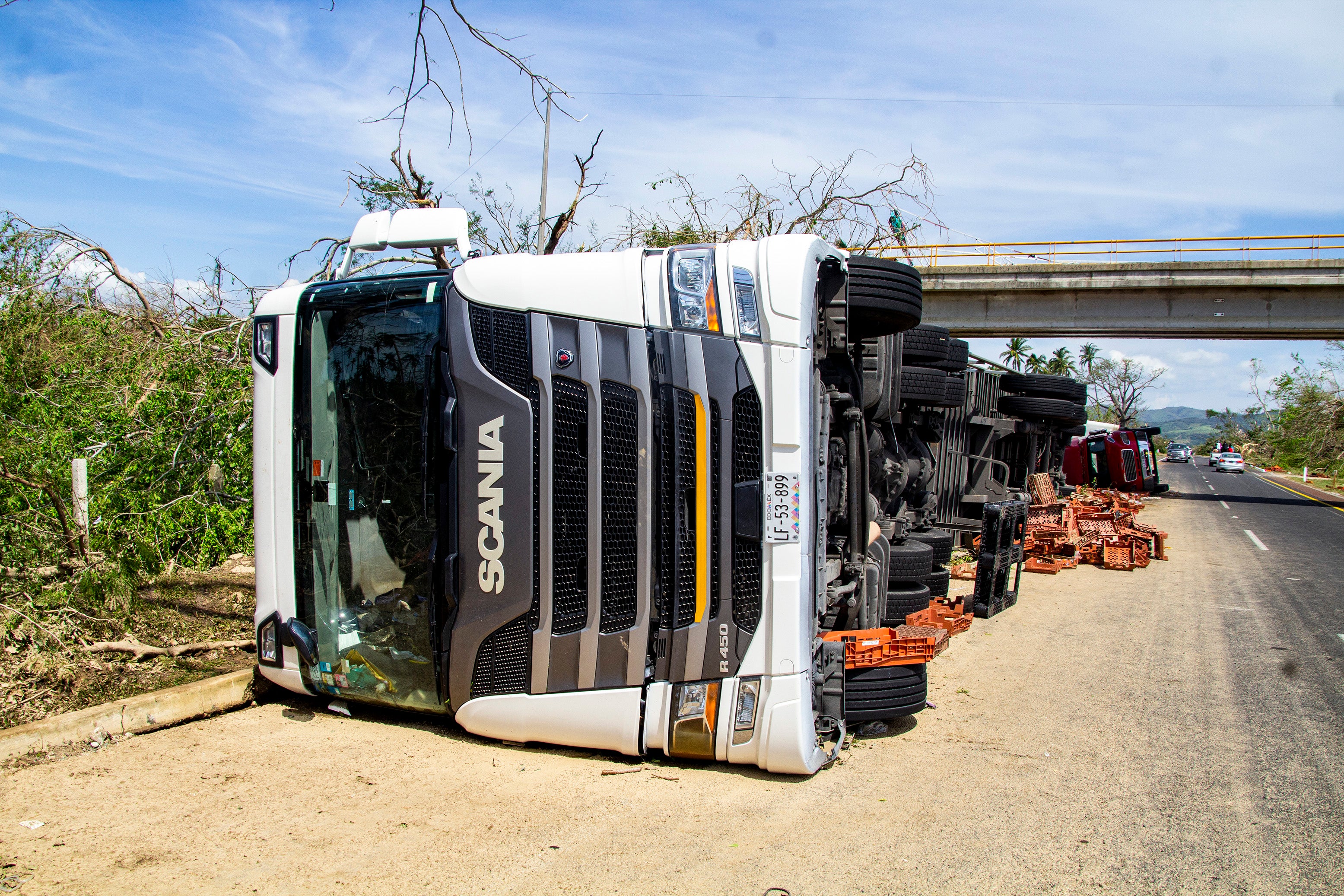 A damaged truck lies on the side of a road after hurricane Otis